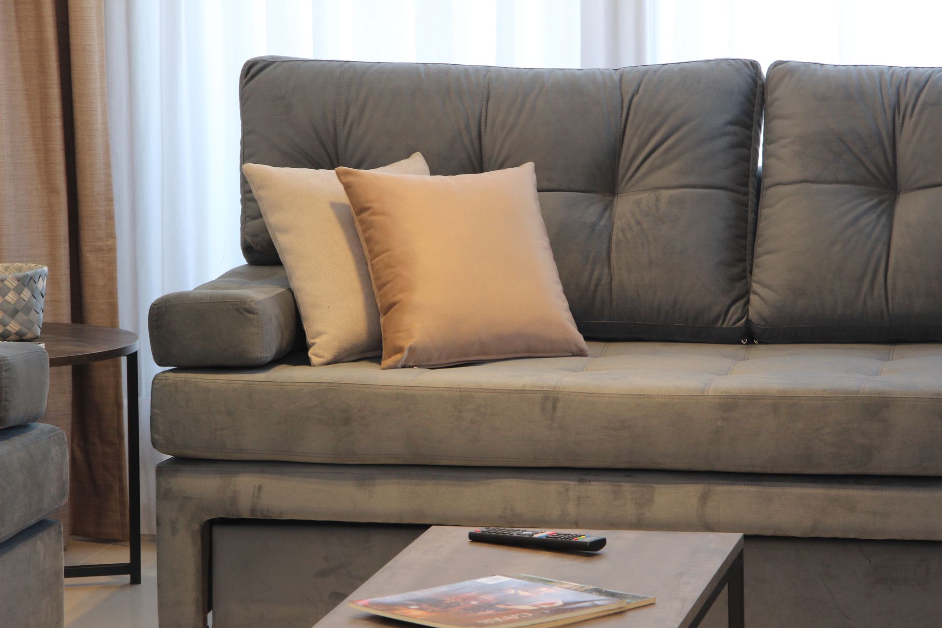 Una sala de estar con un sofá y una mesa con un control remoto encima.