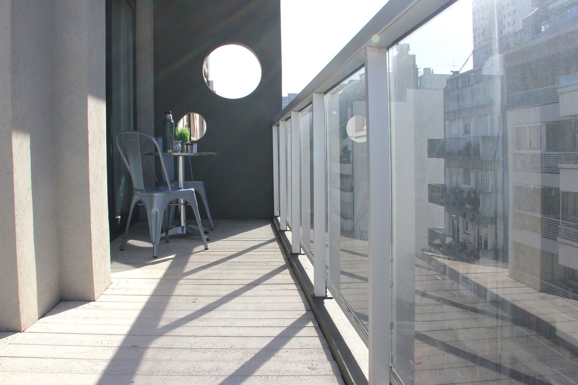 Un balcón con una mesa y sillas y una botella de vino.