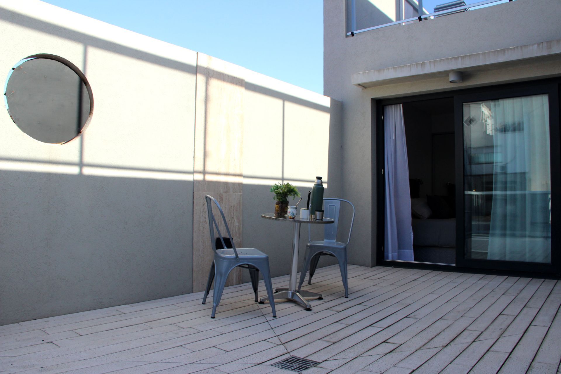 Un balcón con mesa y sillas y una puerta corrediza de vidrio.