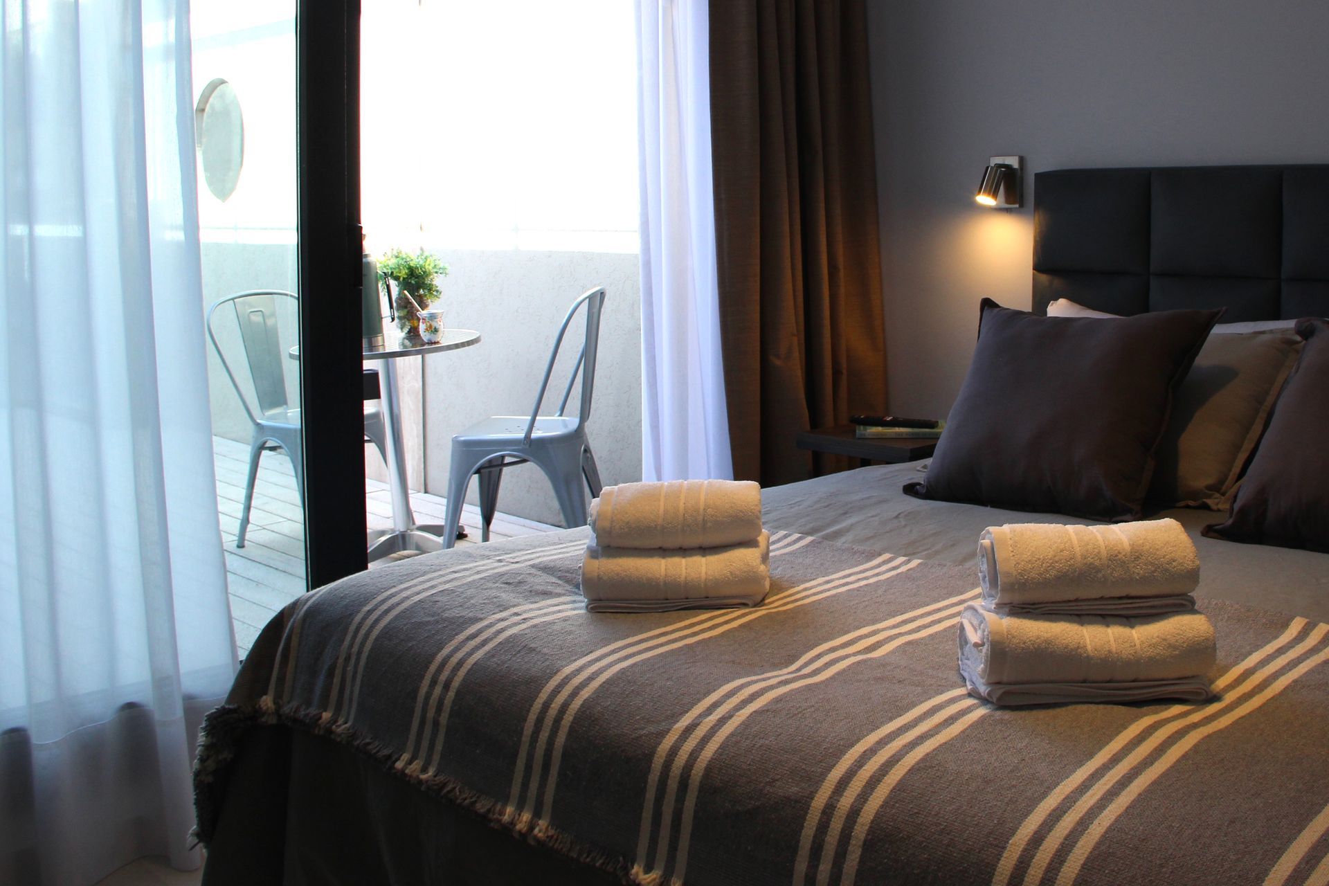 Una habitación de hotel con una cama, sillas y un balcón.