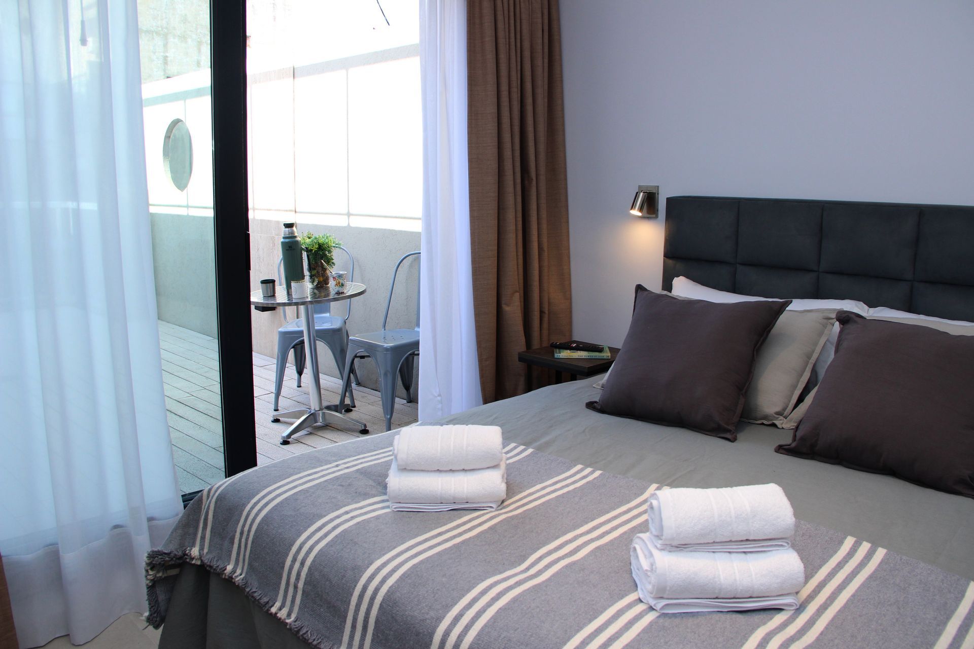 Un dormitorio con una cama grande y un balcón con mesa y sillas.