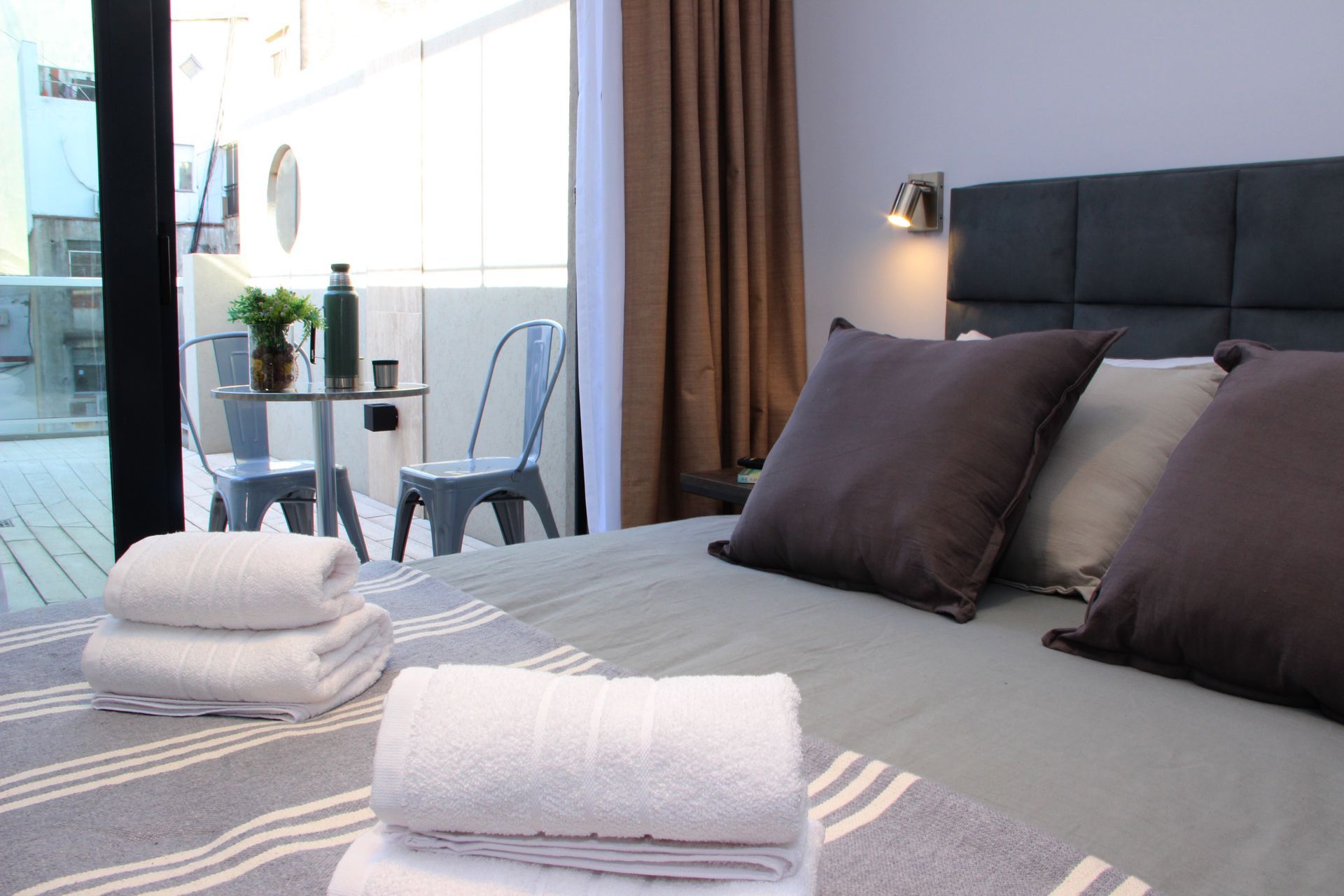 Un dormitorio con una cama, almohadas, toallas y un balcón.