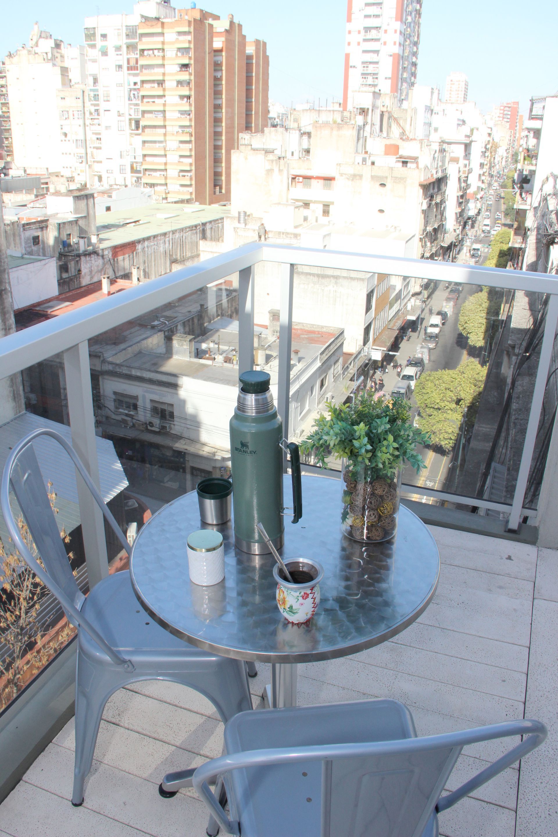 Una pequeña mesa y sillas en un balcón con vista a una ciudad.