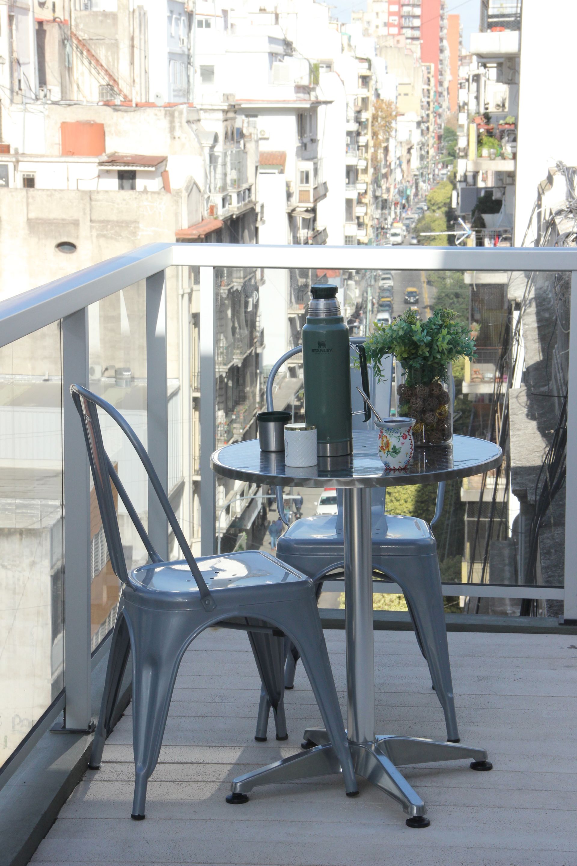 Dos sillas y una mesa en un balcón con vistas a una ciudad.
