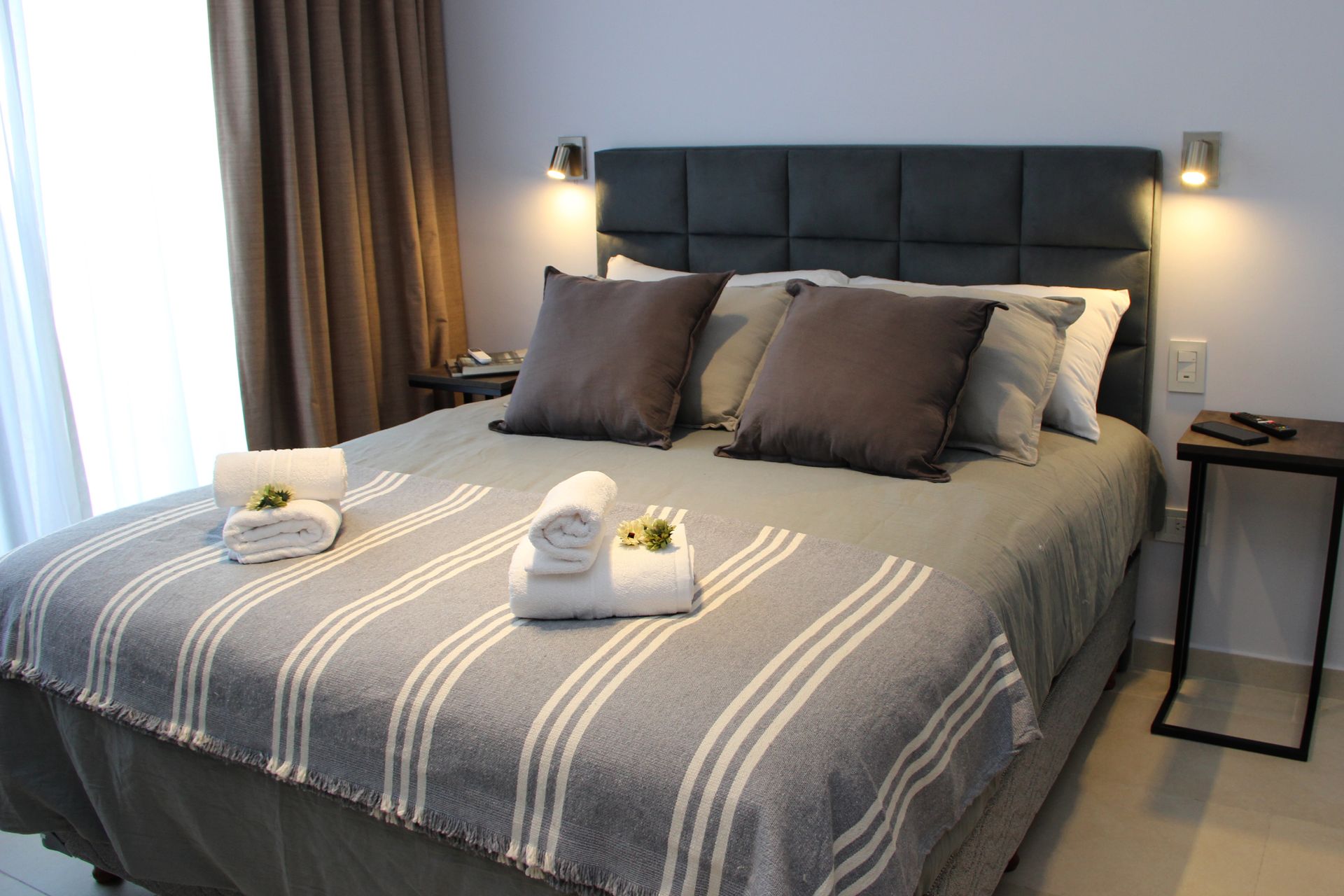 Una cama con una manta a rayas y almohadas en una habitación de hotel.