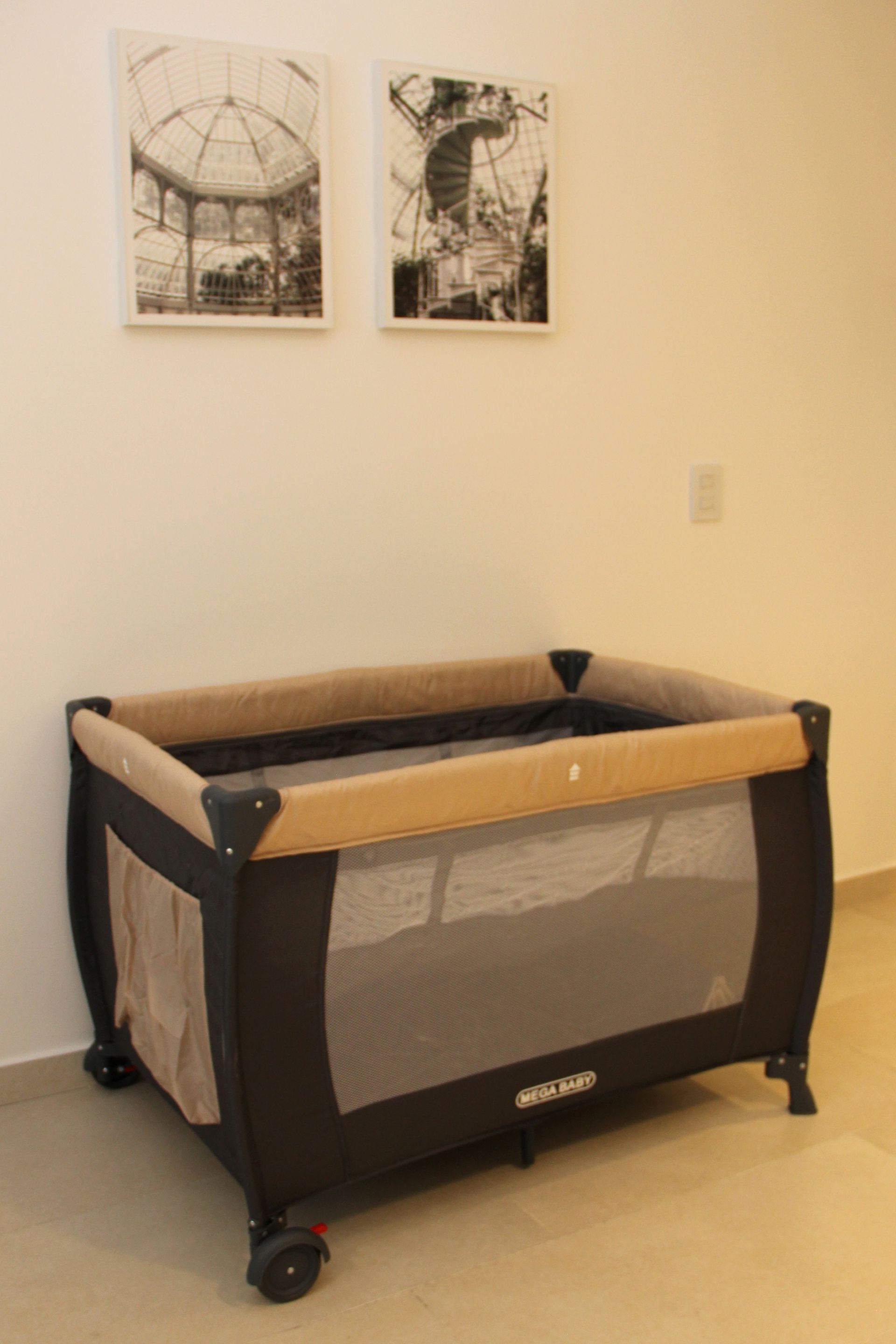 Una cuna de bebé está colocada en una habitación con cuadros en la pared.