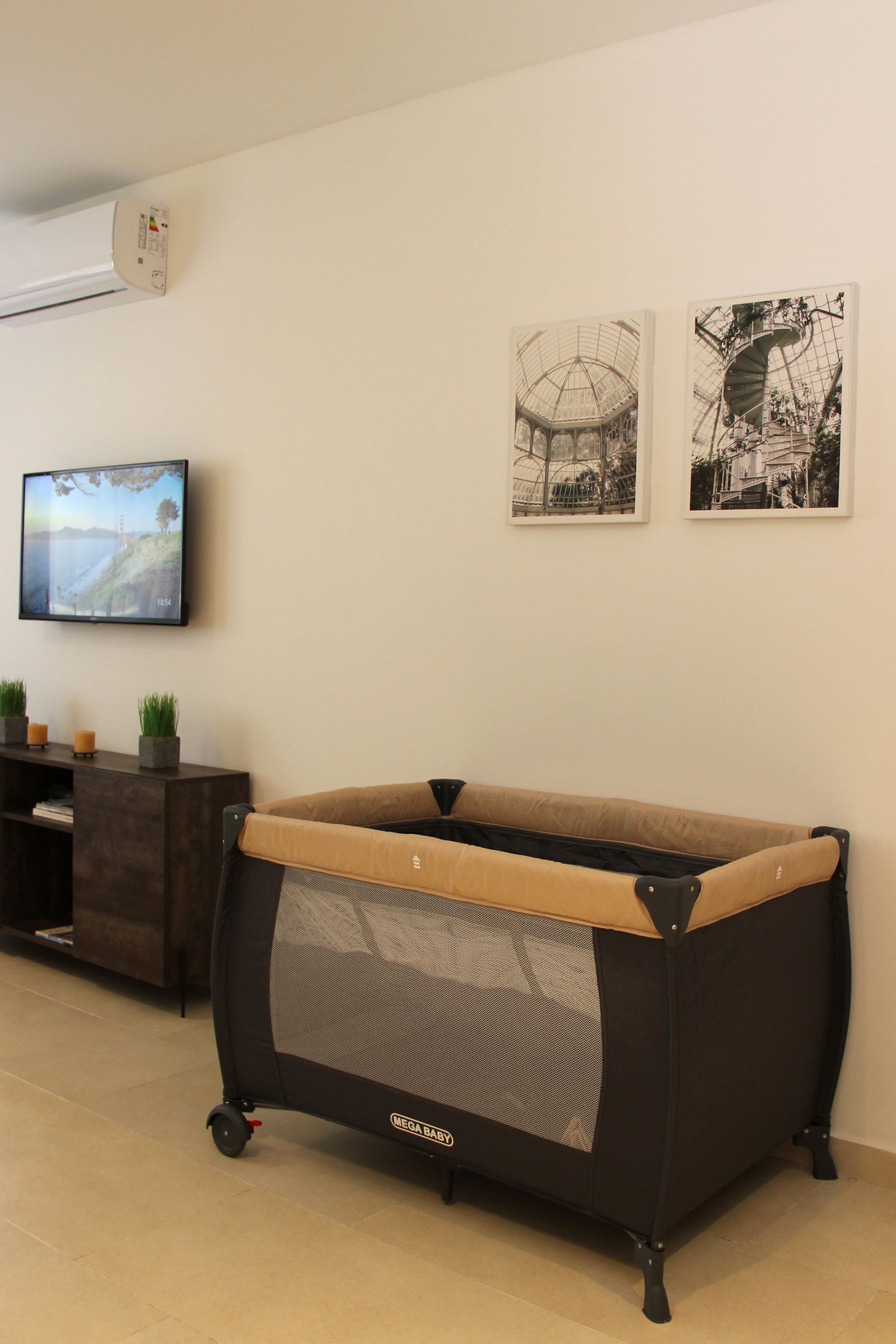 Una cuna de bebé está colocada en una sala de estar al lado de un televisor.