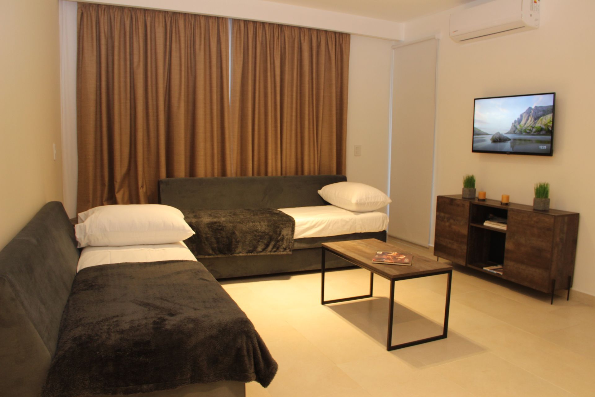Una sala de estar con un sofá, dos camas, una mesa de café y un televisor de pantalla plana.