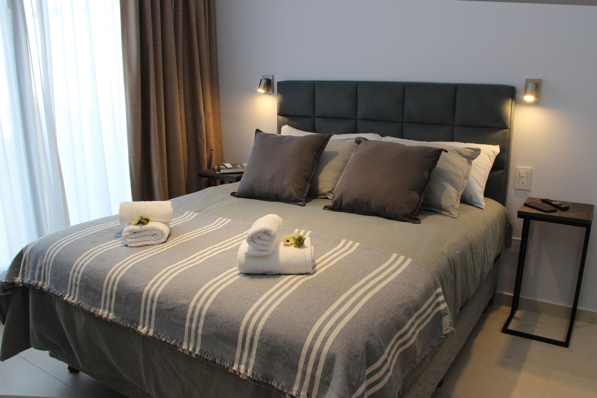 Una cama con una manta a rayas y almohadas en una habitación de hotel.