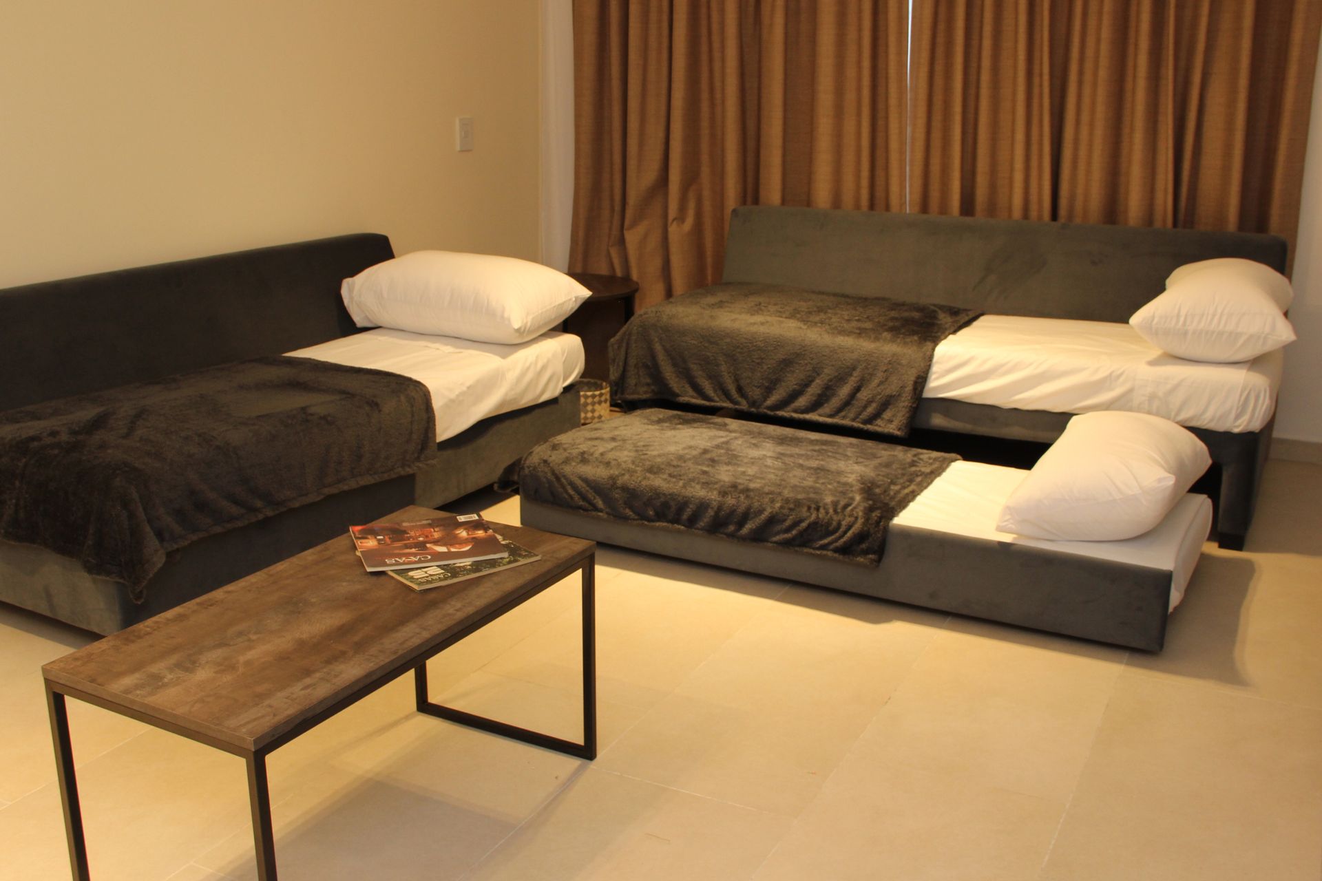 Una sala de estar con dos camas y una mesa de café.