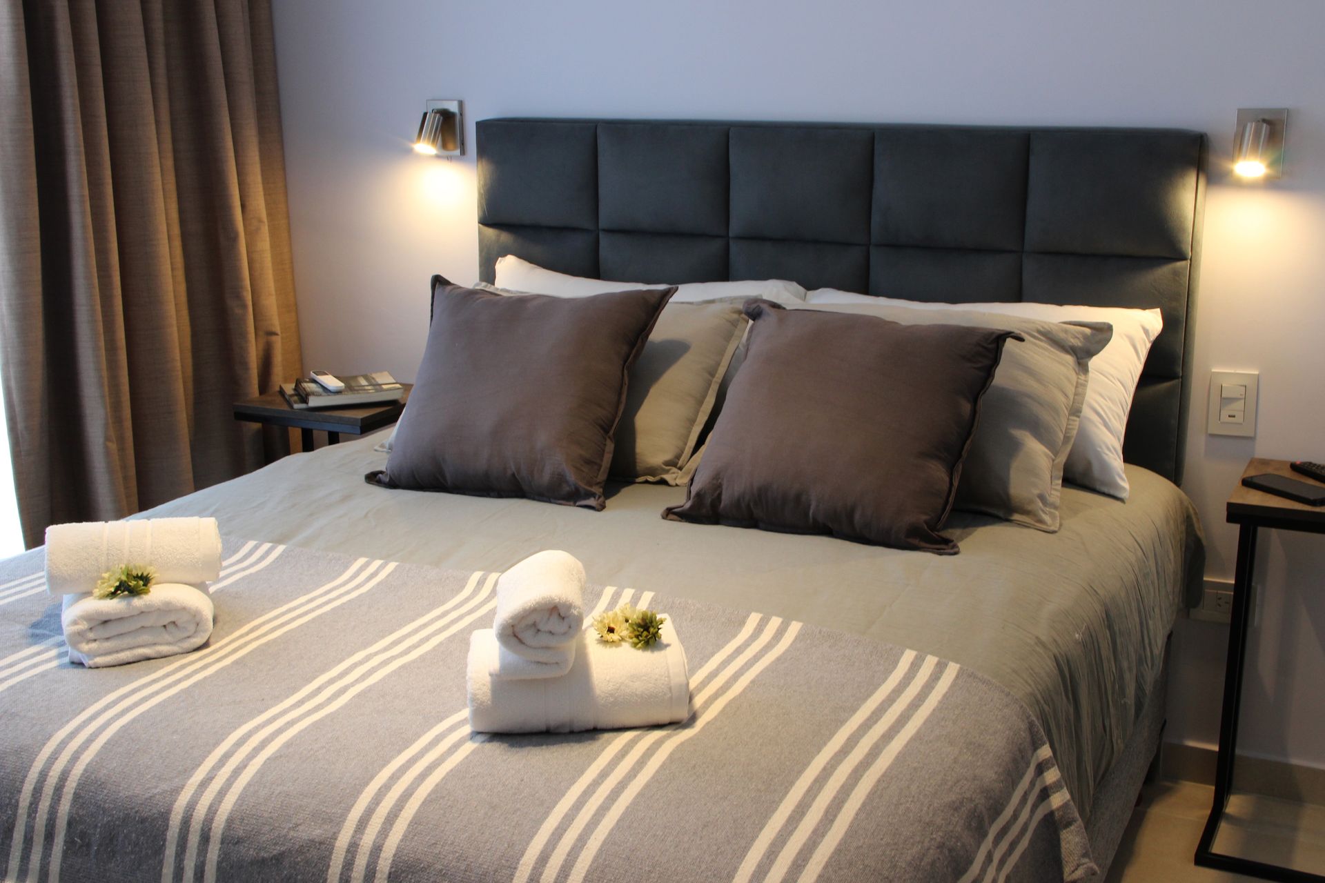 Una cama con una manta a rayas y almohadas en una habitación de hotel.