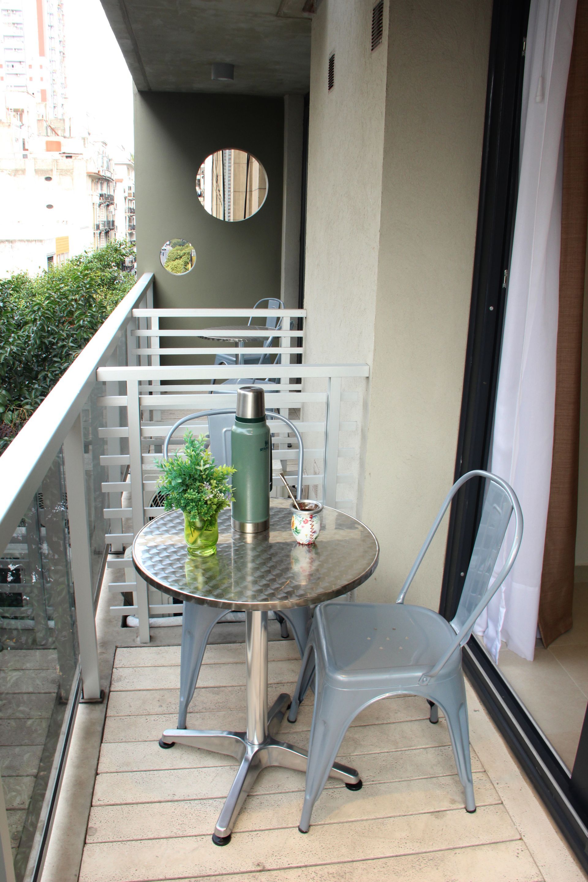 Un pequeño balcón con una mesa y sillas.