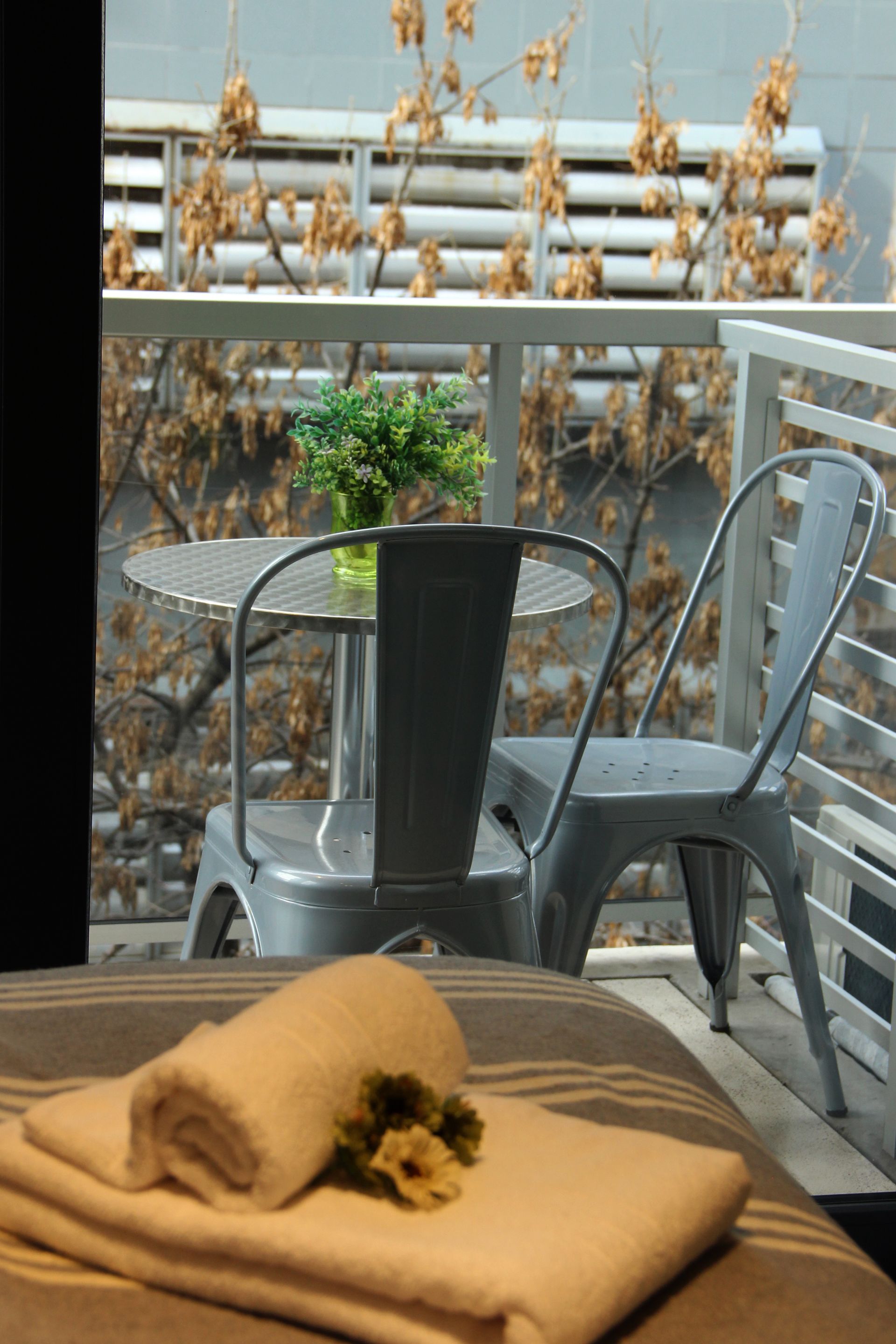 Una pila de toallas se encuentra sobre una cama junto a una mesa y sillas.