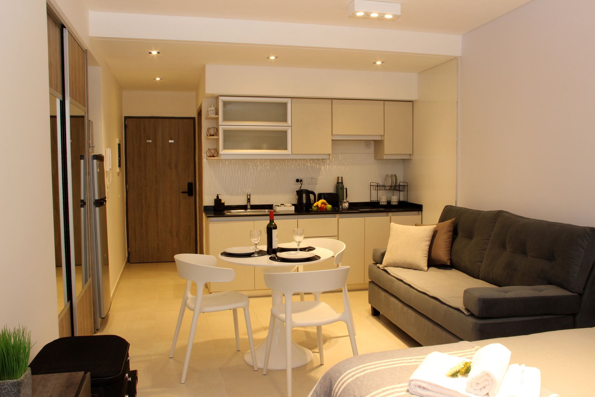 Un pequeño apartamento con sofá, mesa, sillas y cocina.