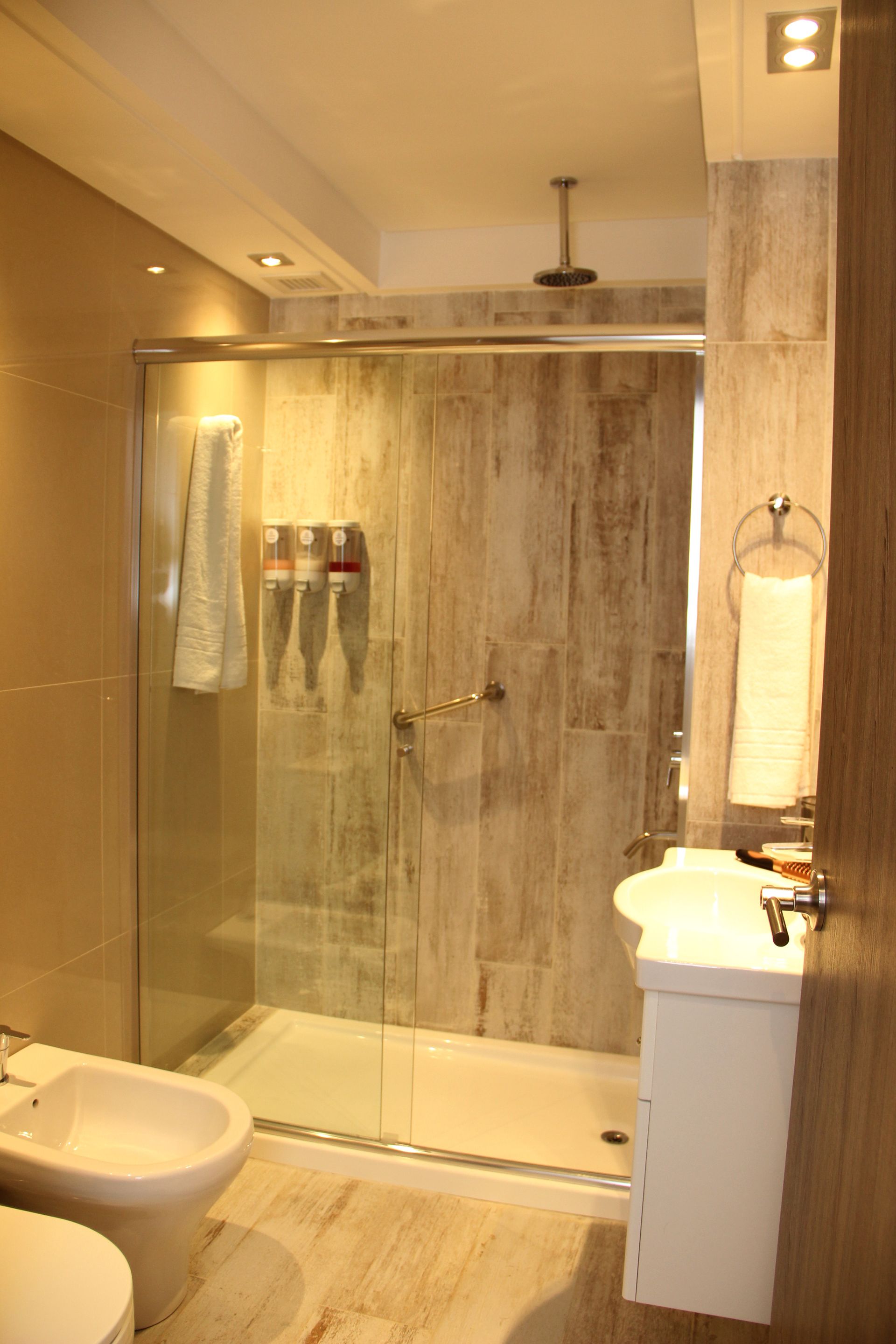 Un baño con inodoro, lavabo y ducha a ras de suelo.