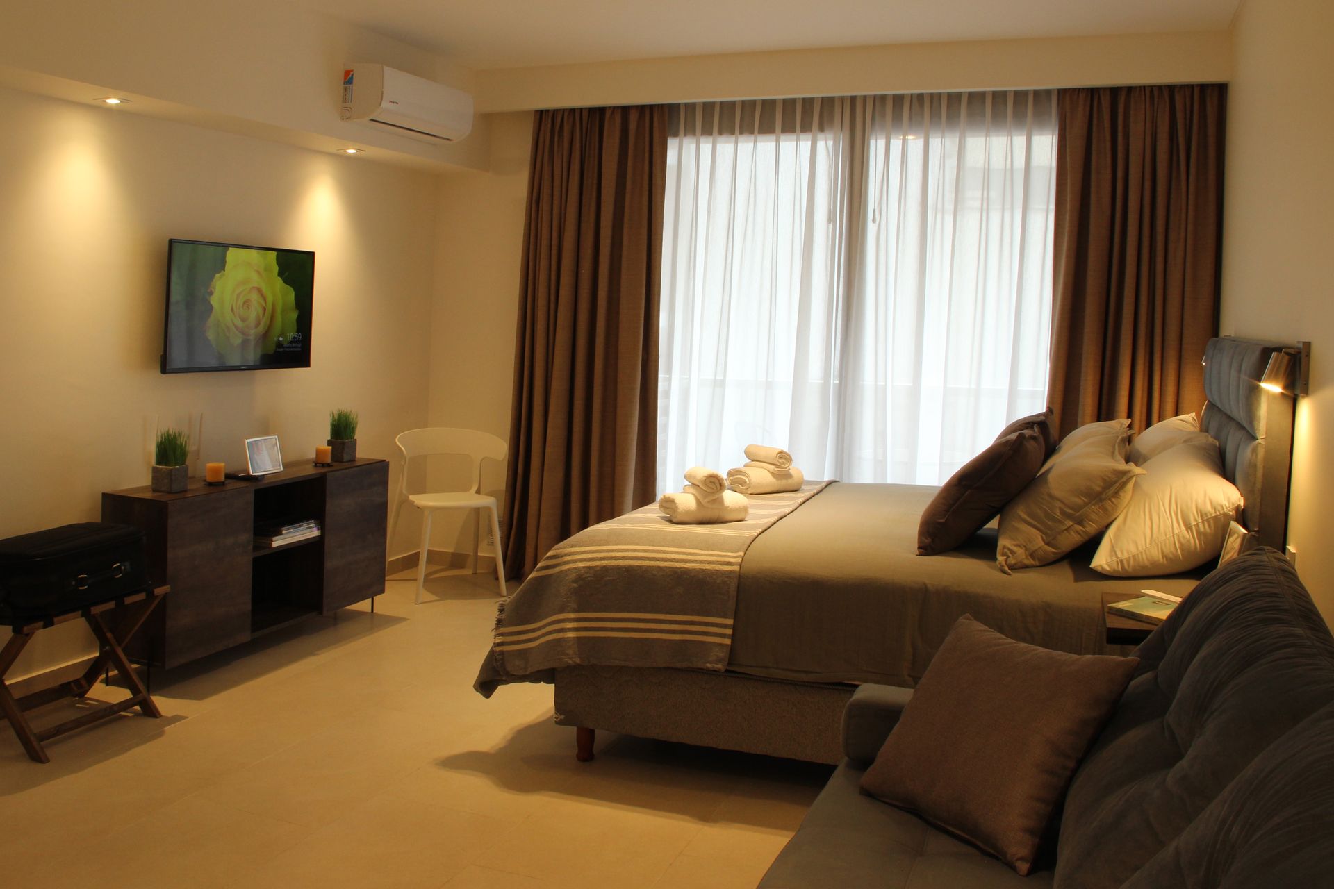 Una habitación de hotel con una cama, un sofá, una silla y una televisión.