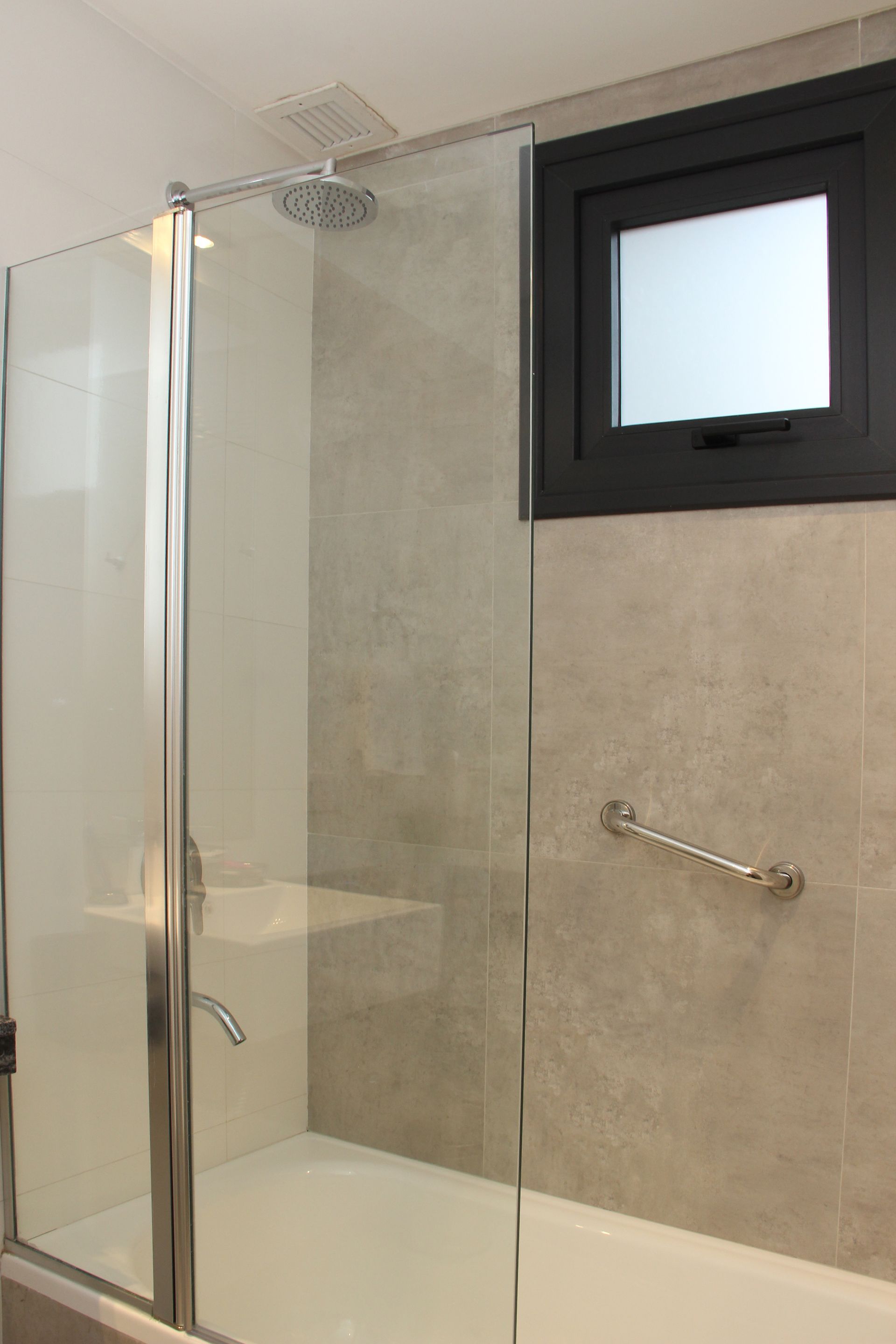 Un baño con bañera y ducha con puerta de cristal.