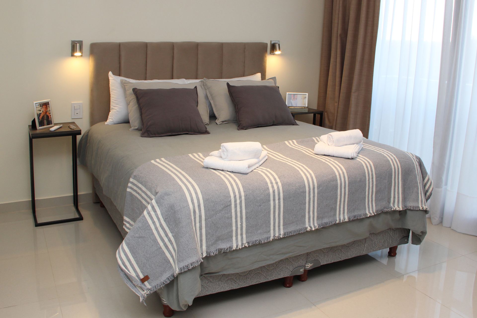 Una cama con una manta a rayas y almohadas en una habitación de hotel.