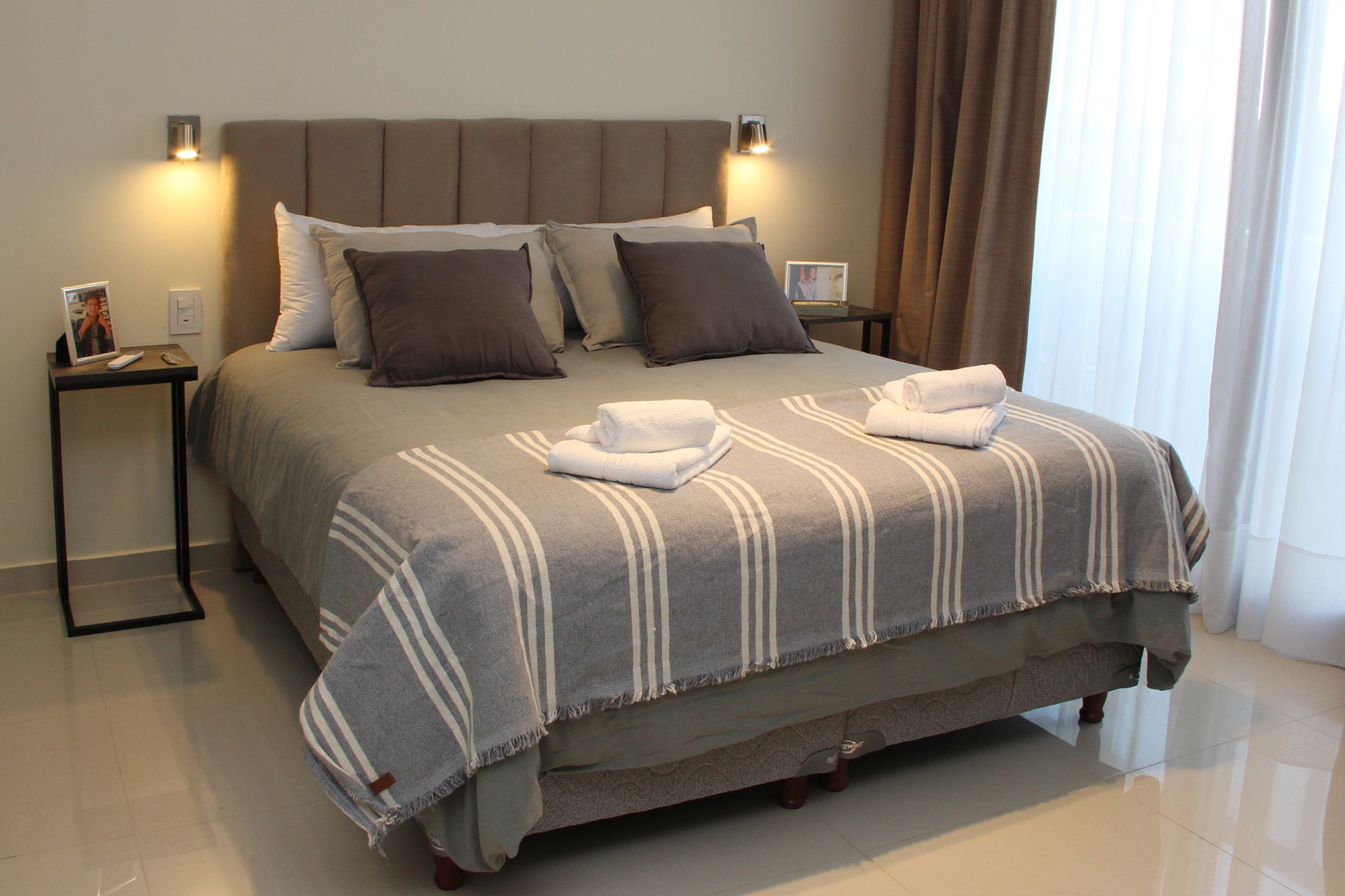 Una cama con una manta a rayas y almohadas en una habitación de hotel.