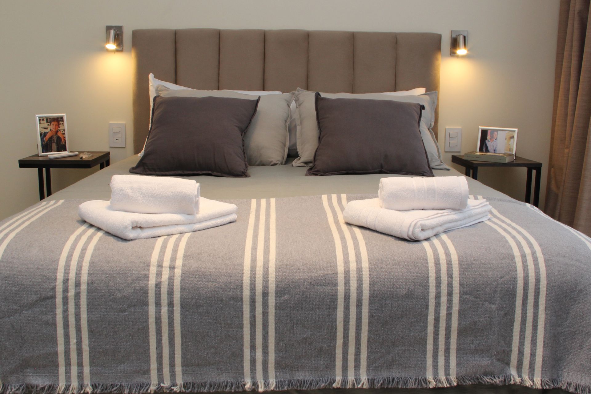 Una cama con una manta a rayas y toallas encima.