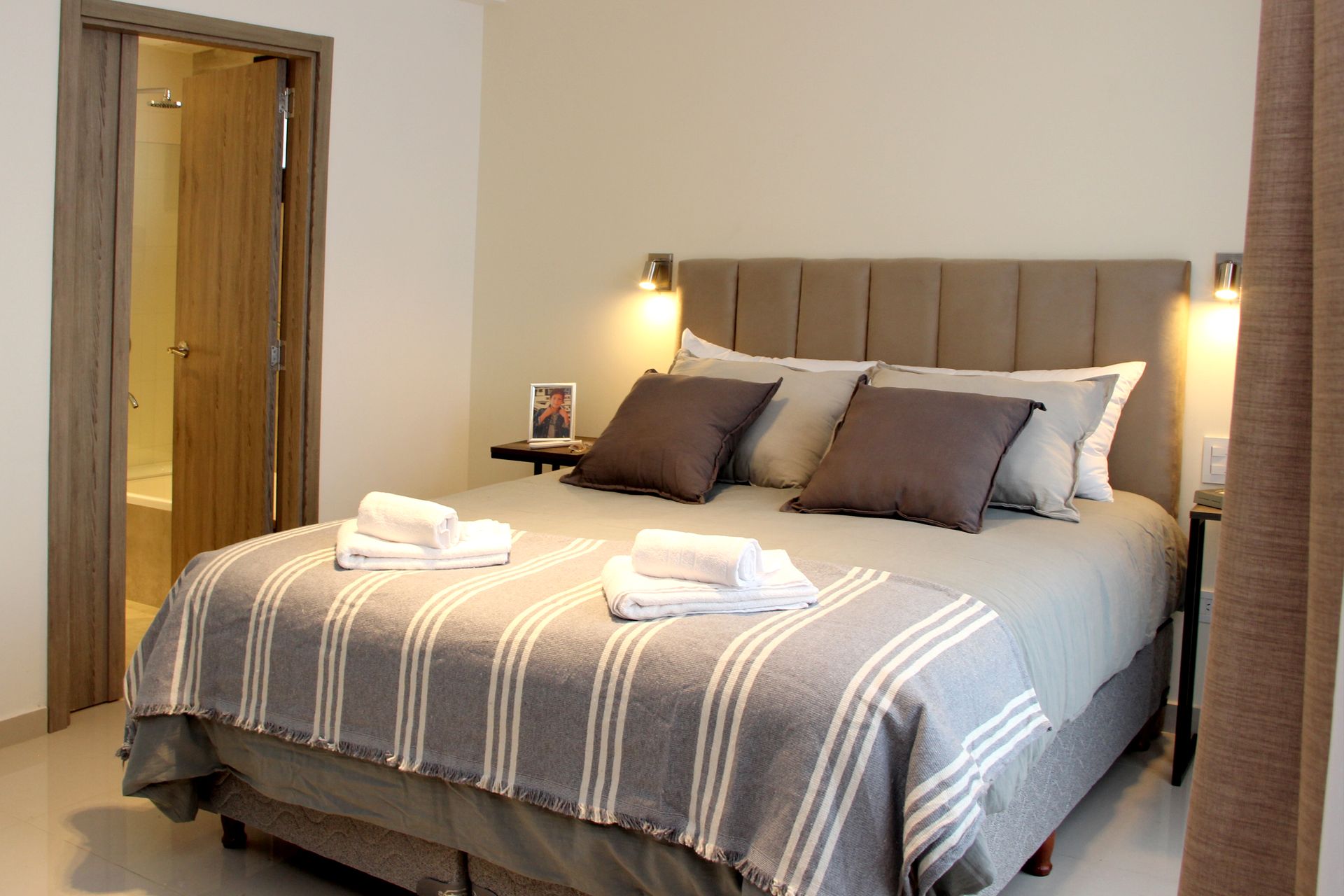 Una cama con una manta a rayas y almohadas en una habitación de hotel.