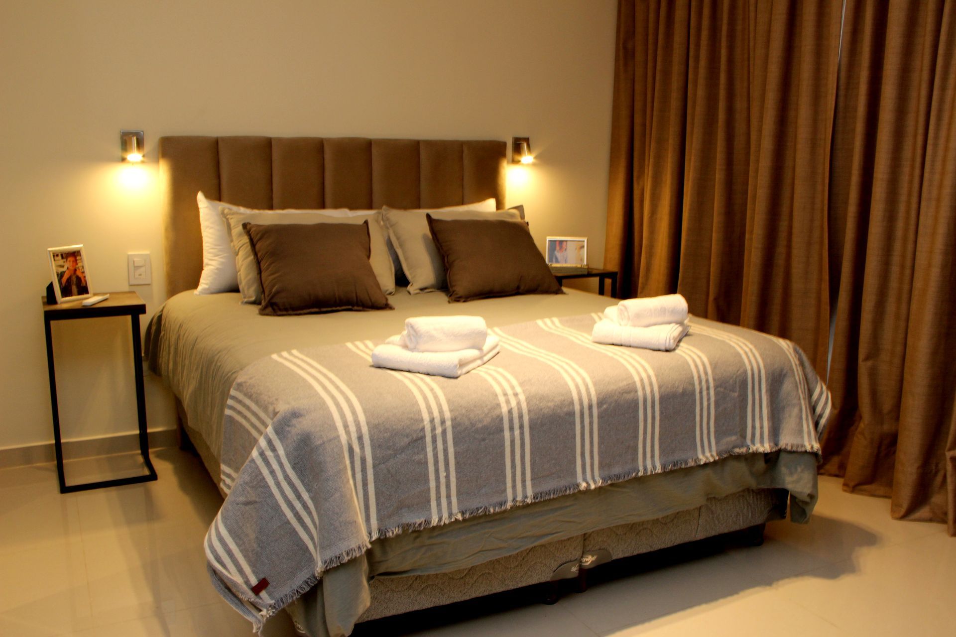 Una cama con una manta a rayas y almohadas en una habitación de hotel.