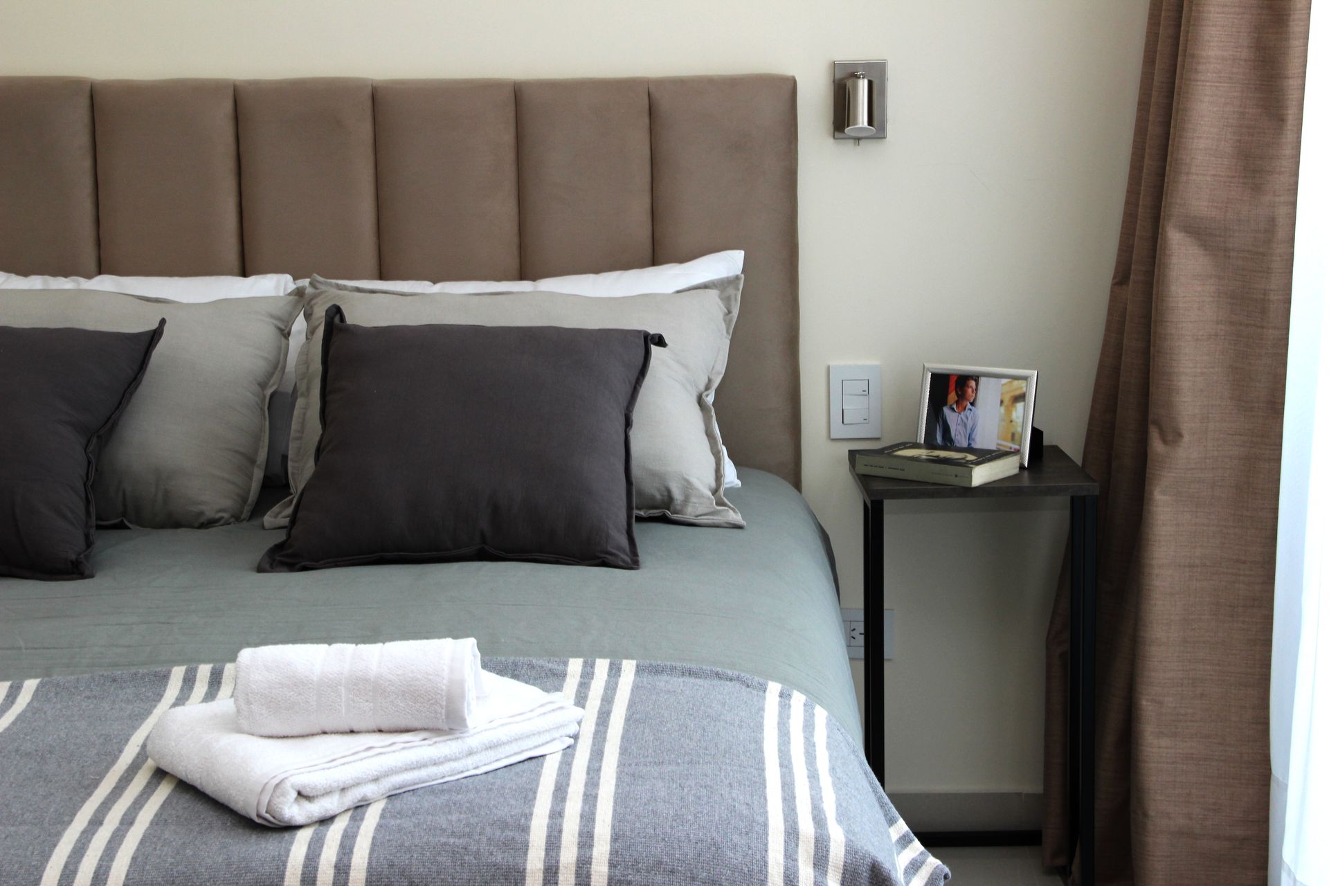 Un dormitorio con una cama y una mesita de noche con un cuadro.