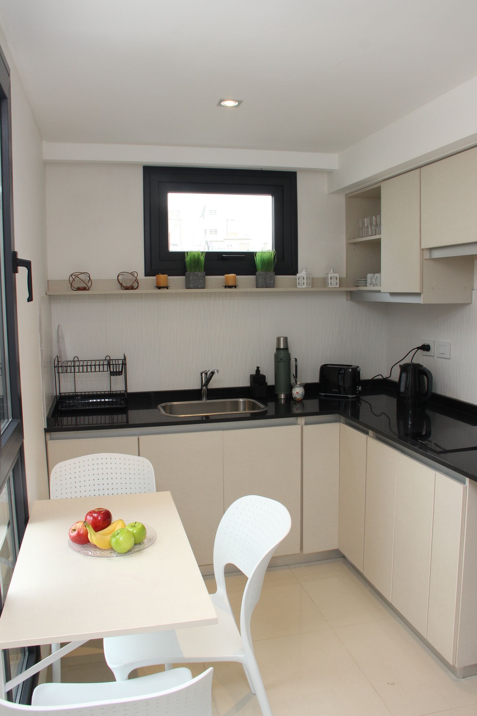 Una cocina con una mesa y sillas y un bol de fruta en la mesa.
