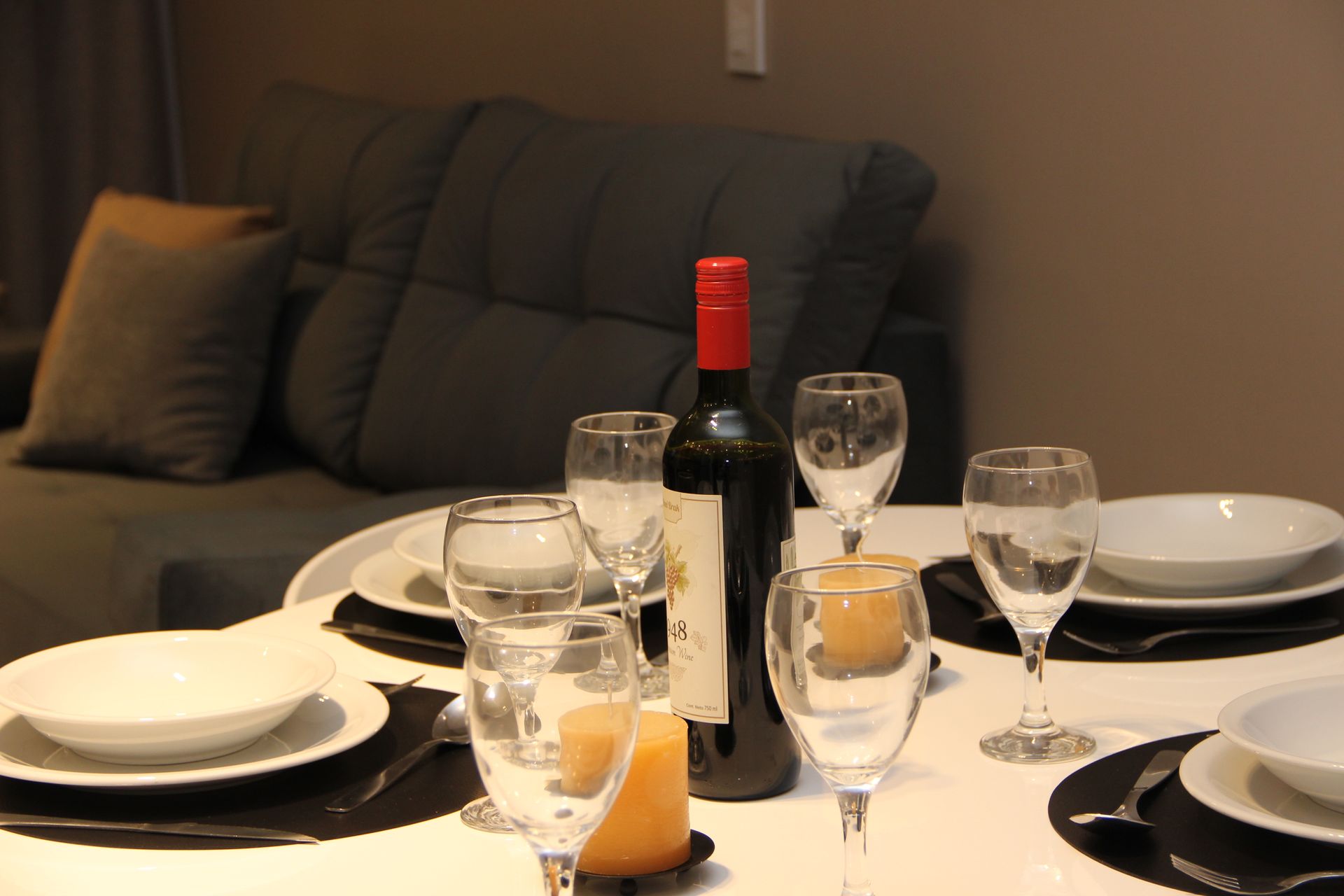 Una botella de vino reposa sobre una mesa con platos y vasos.