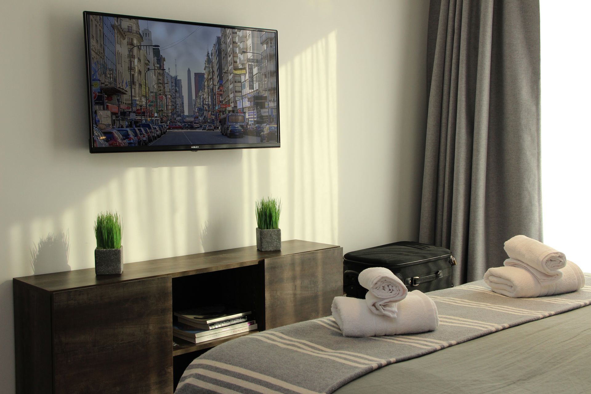 Un dormitorio con una cama y un televisor de pantalla plana en la pared.