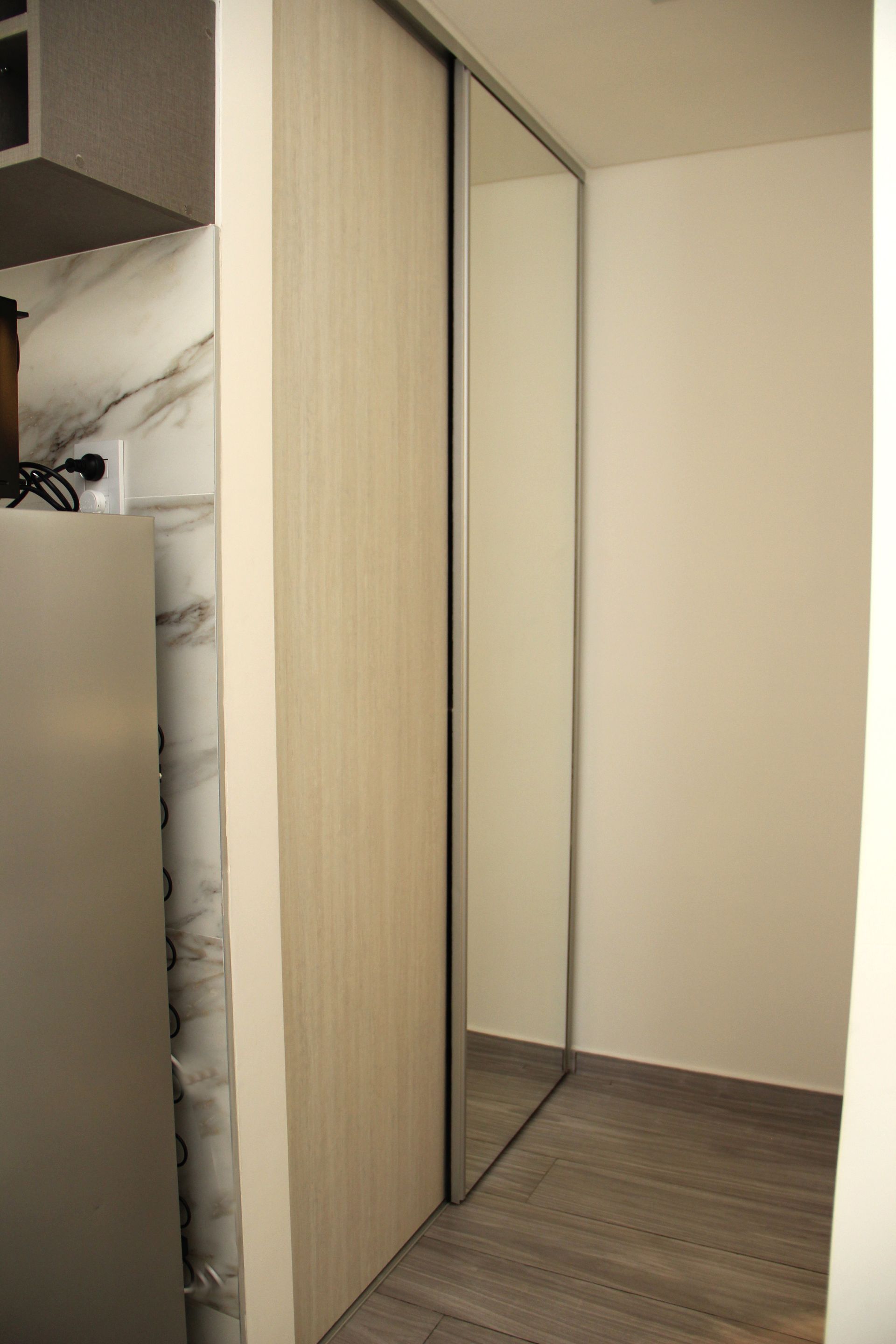 Un pasillo con una puerta corrediza de vidrio y un espejo.