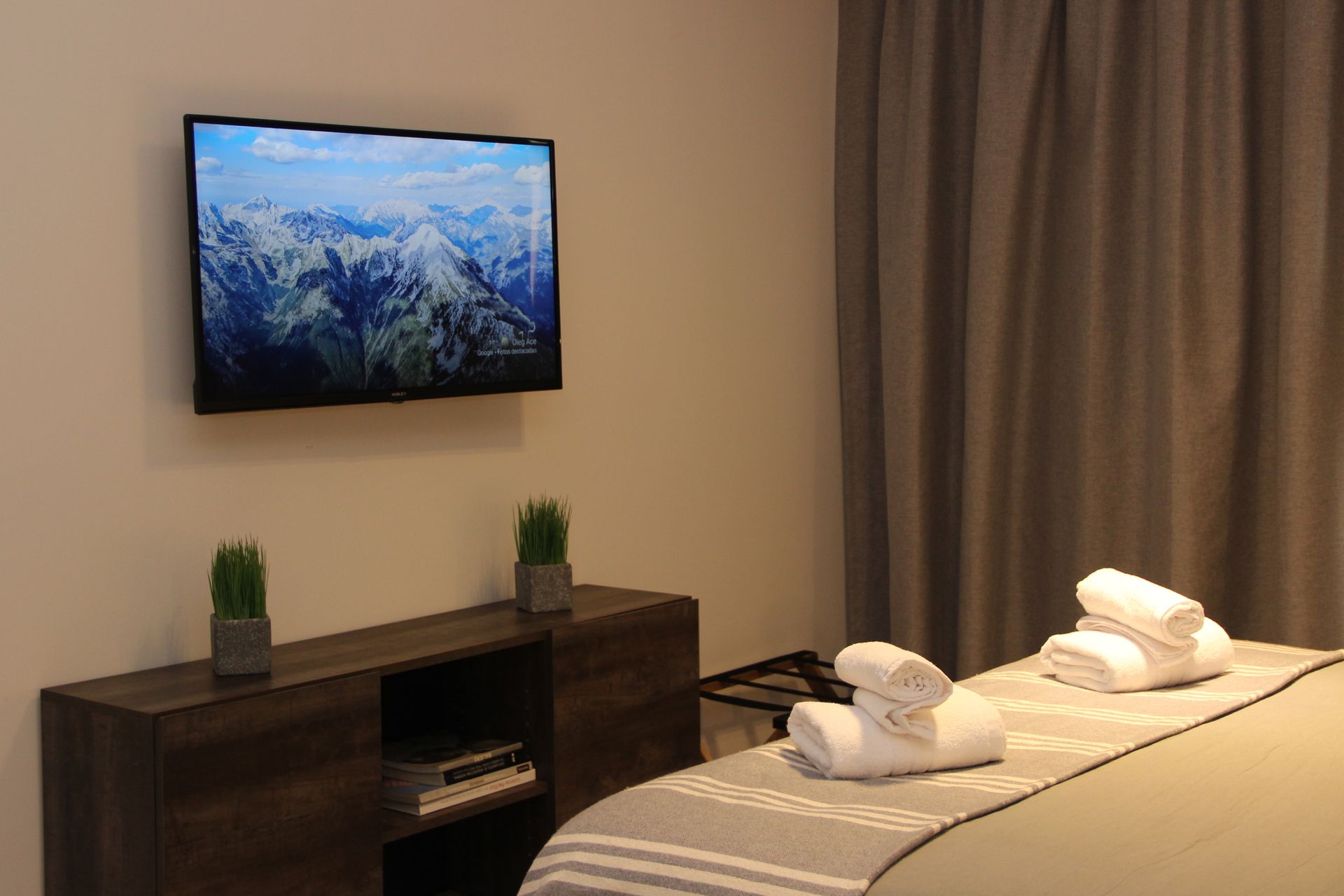 Un dormitorio con una cama y un televisor de pantalla plana en la pared.