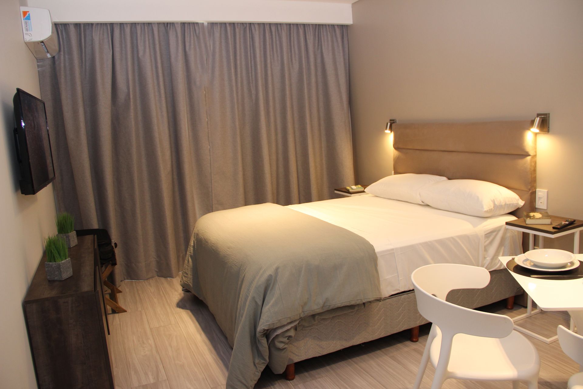 Una habitación de hotel con una cama, sillas, mesa y televisión.