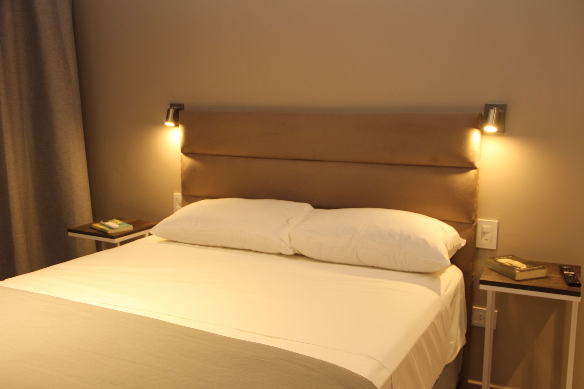 Una cama con sábanas blancas y almohadas en una habitación de hotel.