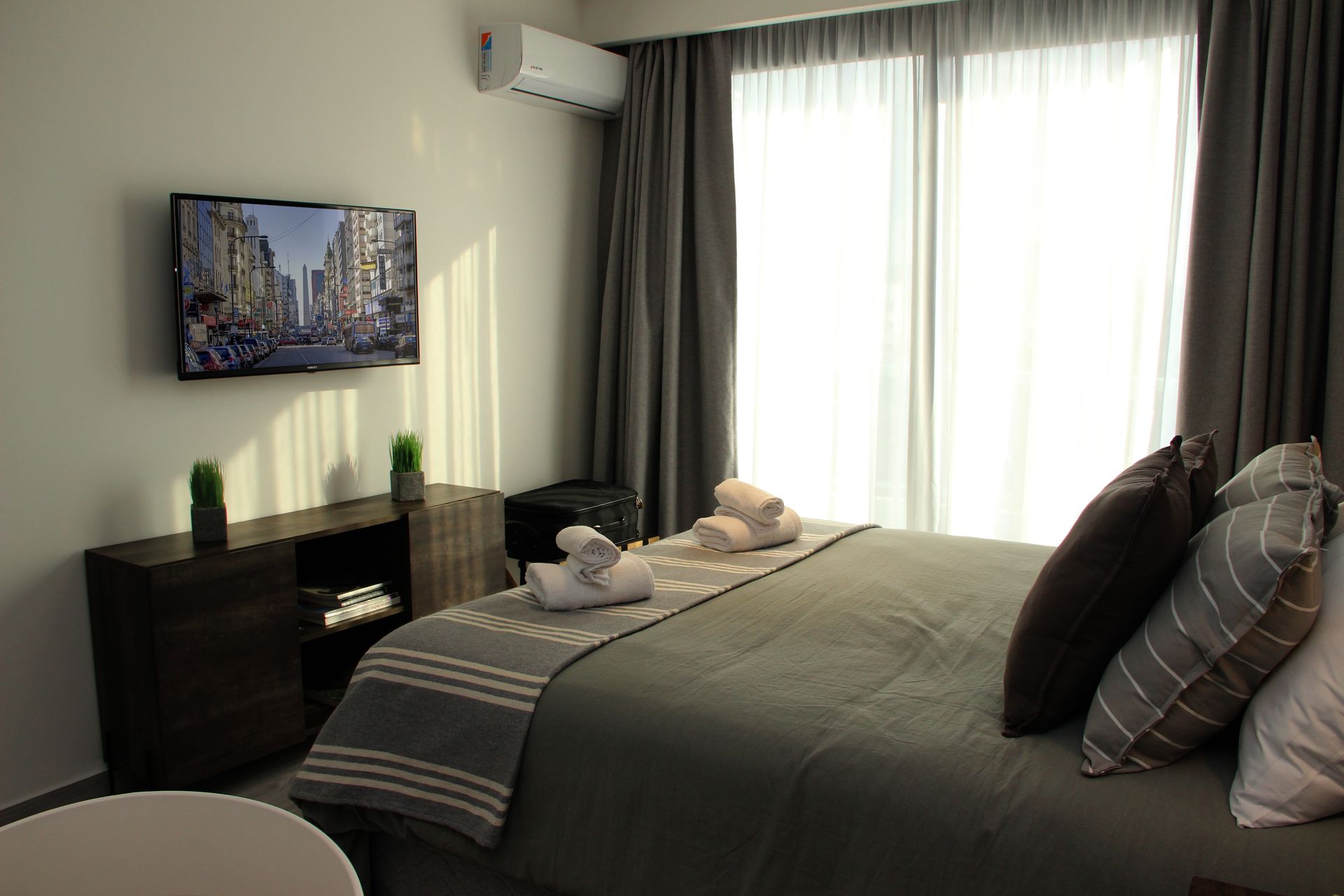 Una habitación de hotel con cama, televisión y grandes ventanales.