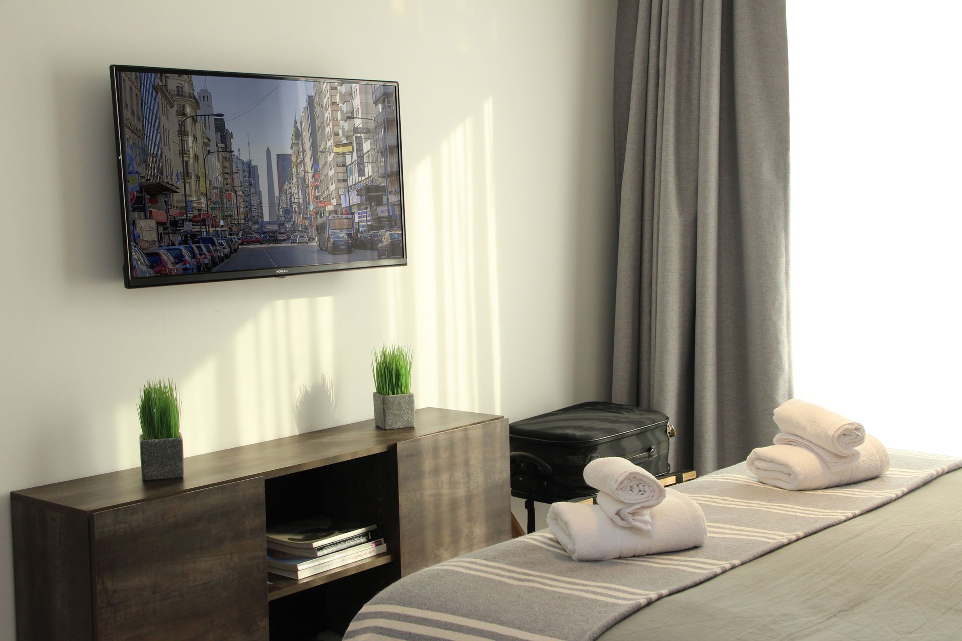 Un dormitorio con un televisor de pantalla plana grande en la pared sobre la cama.