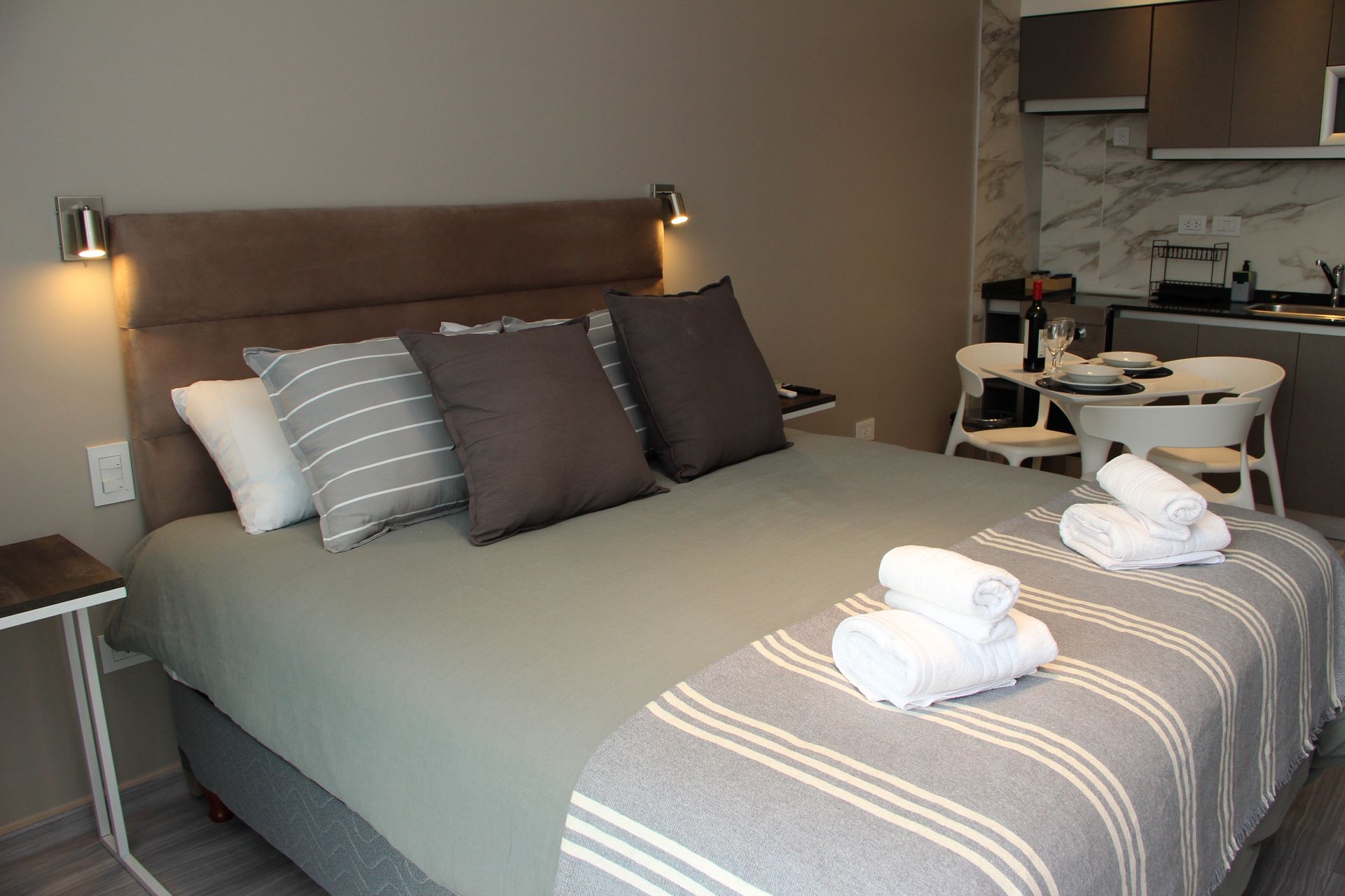 Un dormitorio con una cama grande y una cocina al fondo.