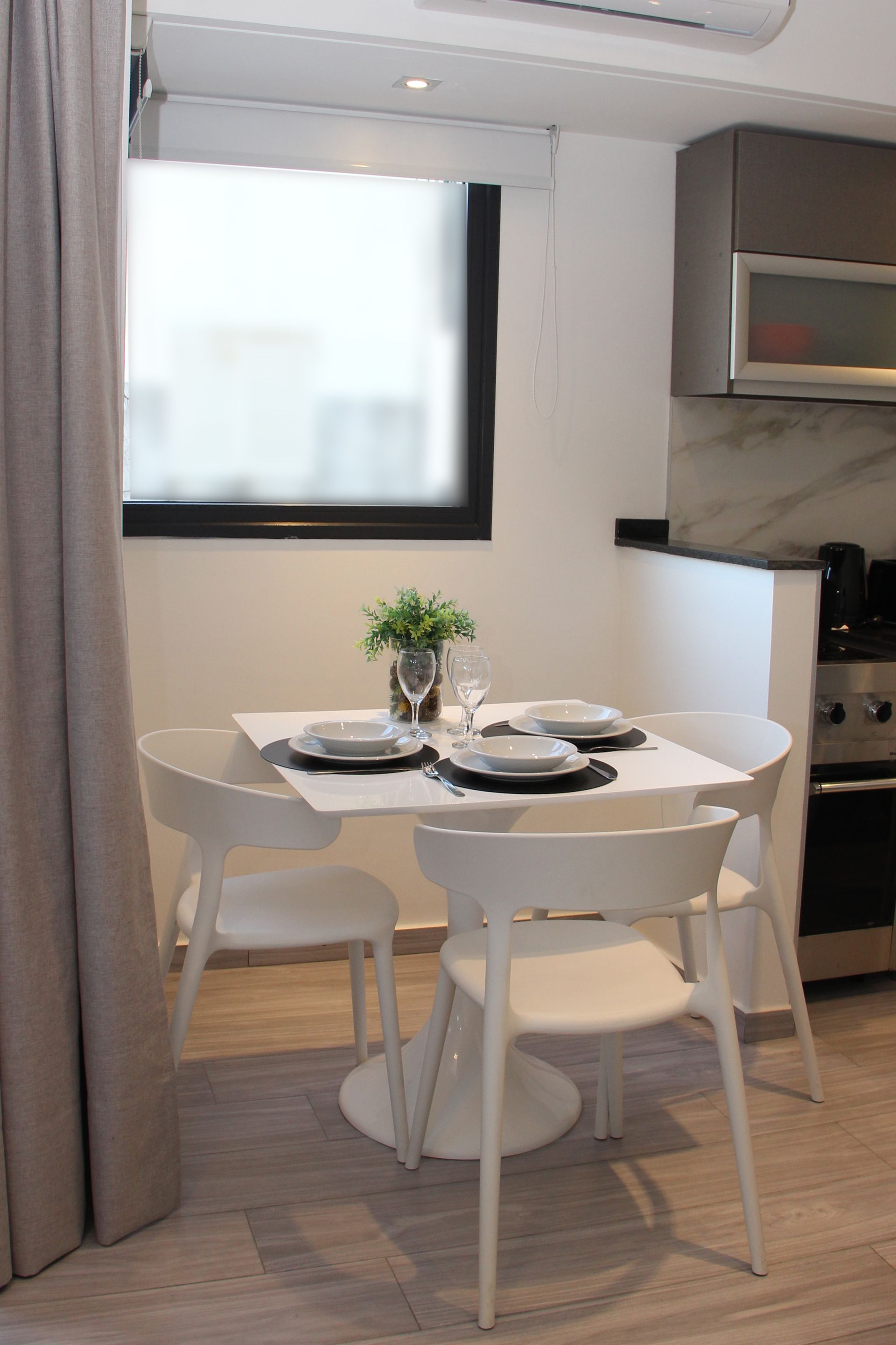 Un comedor con una mesa y sillas frente a una ventana.