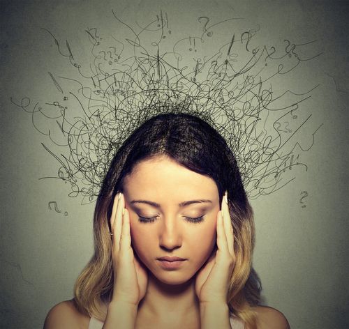 A woman is holding her head with a bunch of question marks coming out of her head