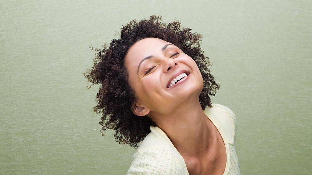 Smiling woman with eyes closed, symbolizing calm and confidence from affirmations.