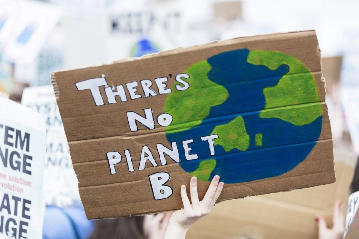 Protest sign saying “There’s No Planet B,” highlighting climate change and mental health stress.