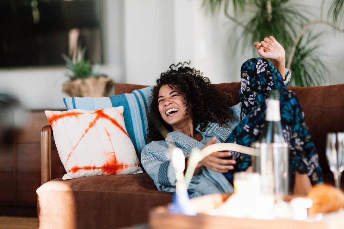 Smiling woman relaxing on a couch at home, symbolizing relief and calm after practicing anxiety-reducing exercises.