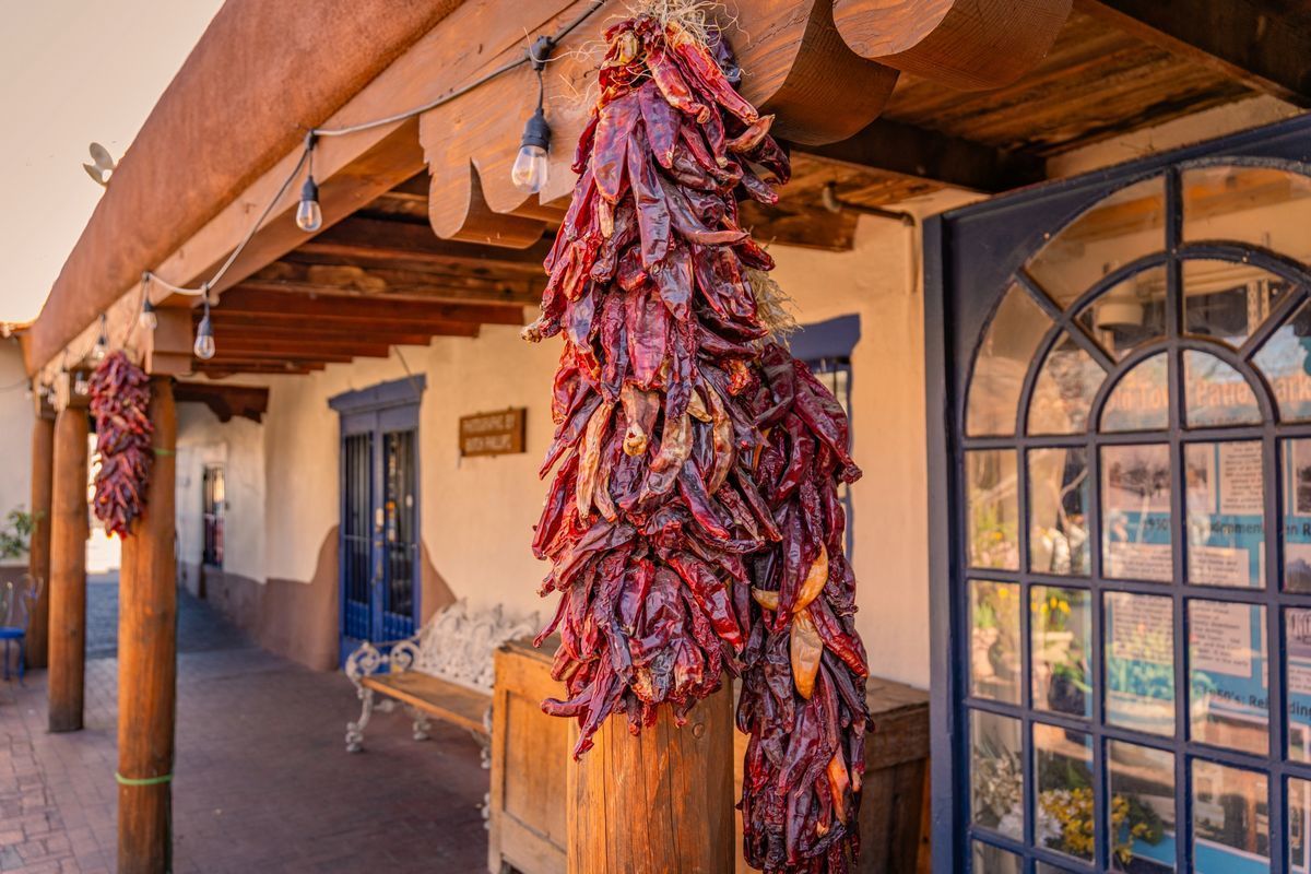 Red chile ristras hanging from an adobe building in Old Town Albuquerque, a relaxing place to walk on a mental health day.
