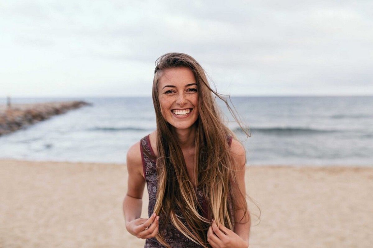 Smiling young woman enjoying time at the beach, symbolizing relaxation and benefits of a mental health day.