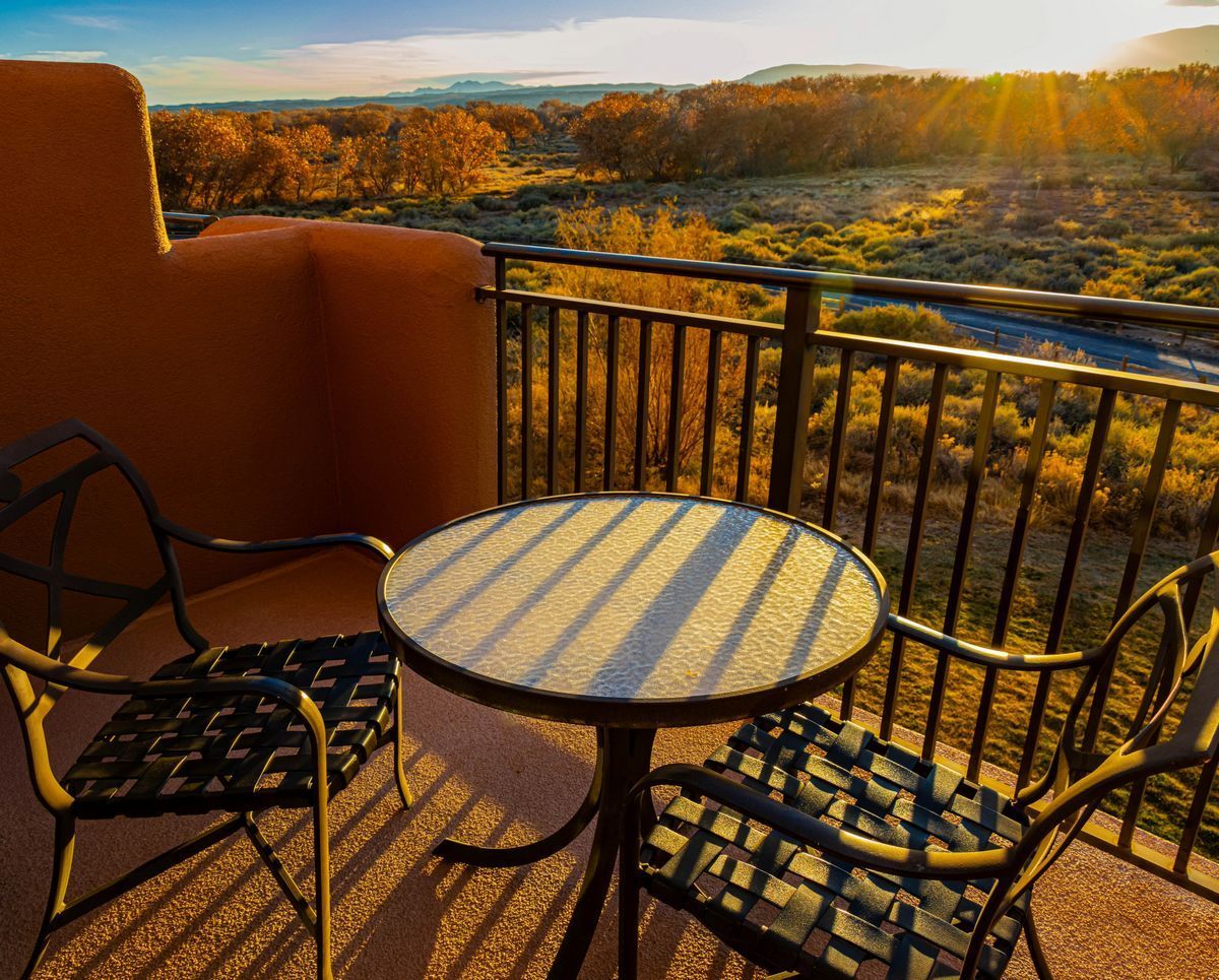 Scenic New Mexico sunrise view from a balcony with table and chairs, symbolizing calm morning routine.