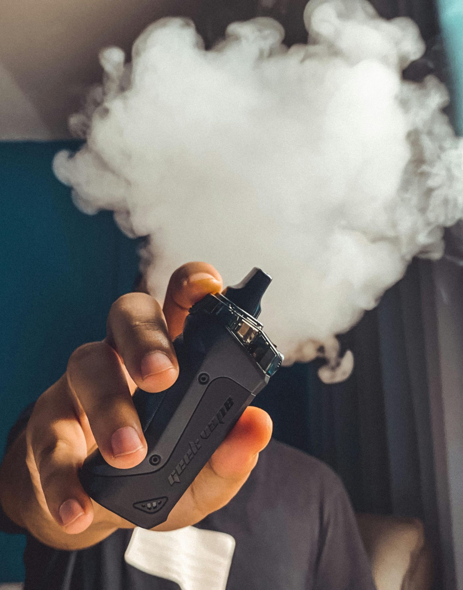 A hand holding a black vaping device.