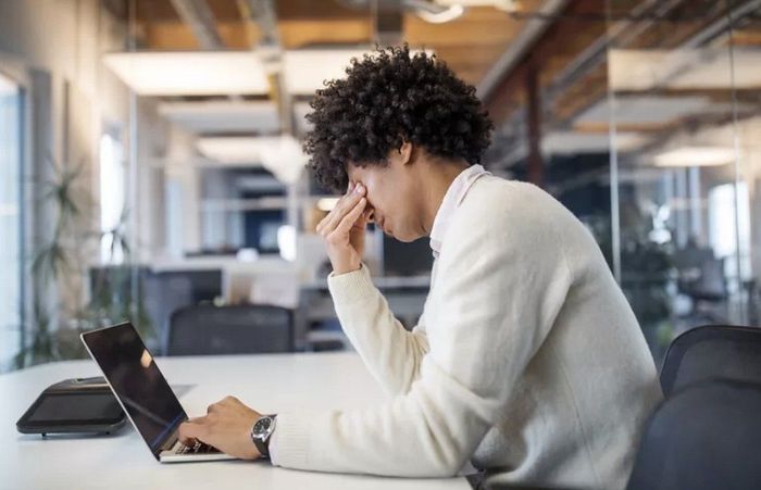 A man is sitting at a desk using a laptop computer.