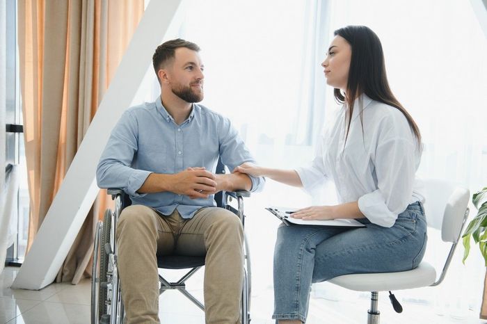 A man in a wheelchair is talking to a female doctor.