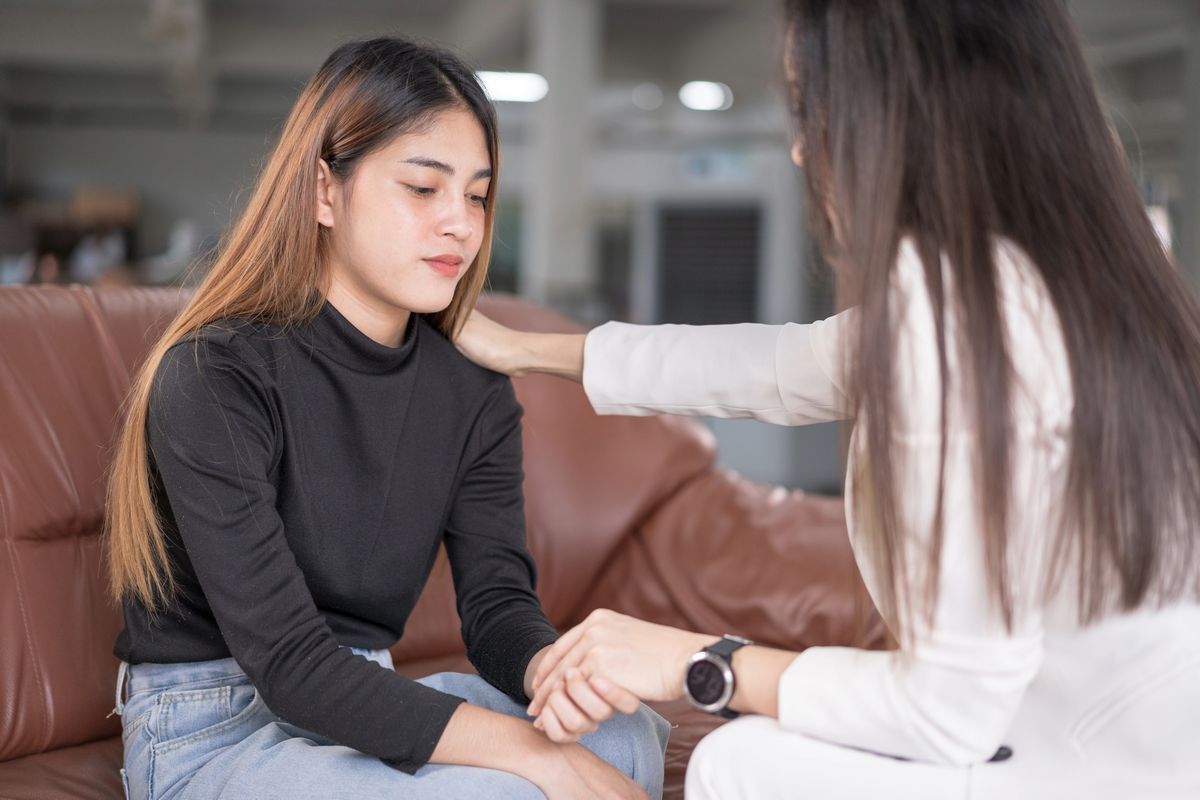 Woman receiving emotional support from counselor after experiencing discrimination.