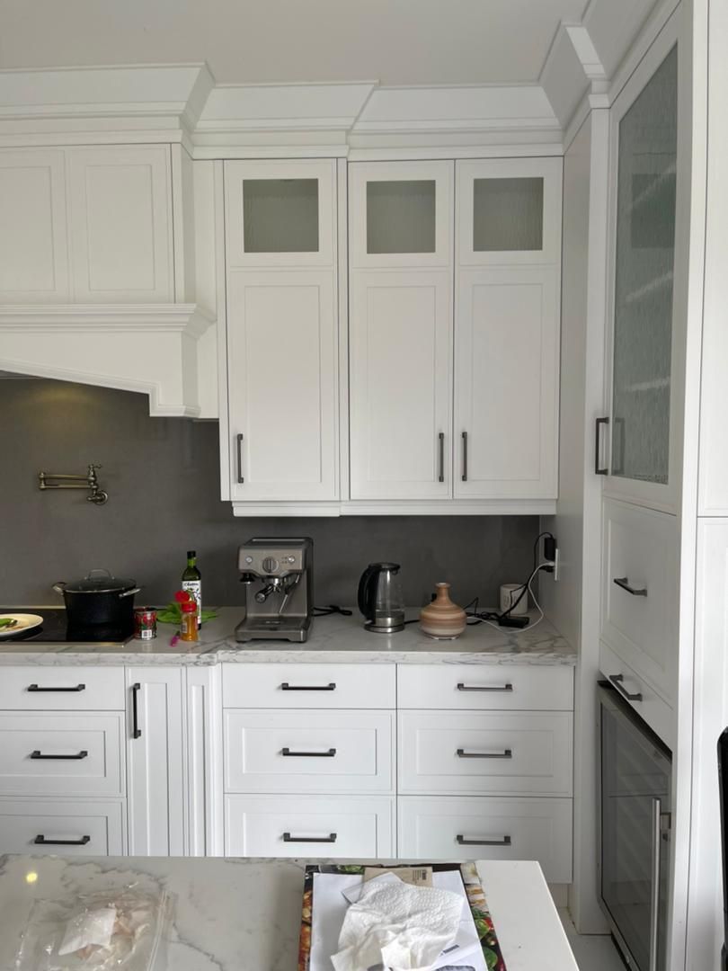 A kitchen with white cabinets and a coffee maker on the counter.